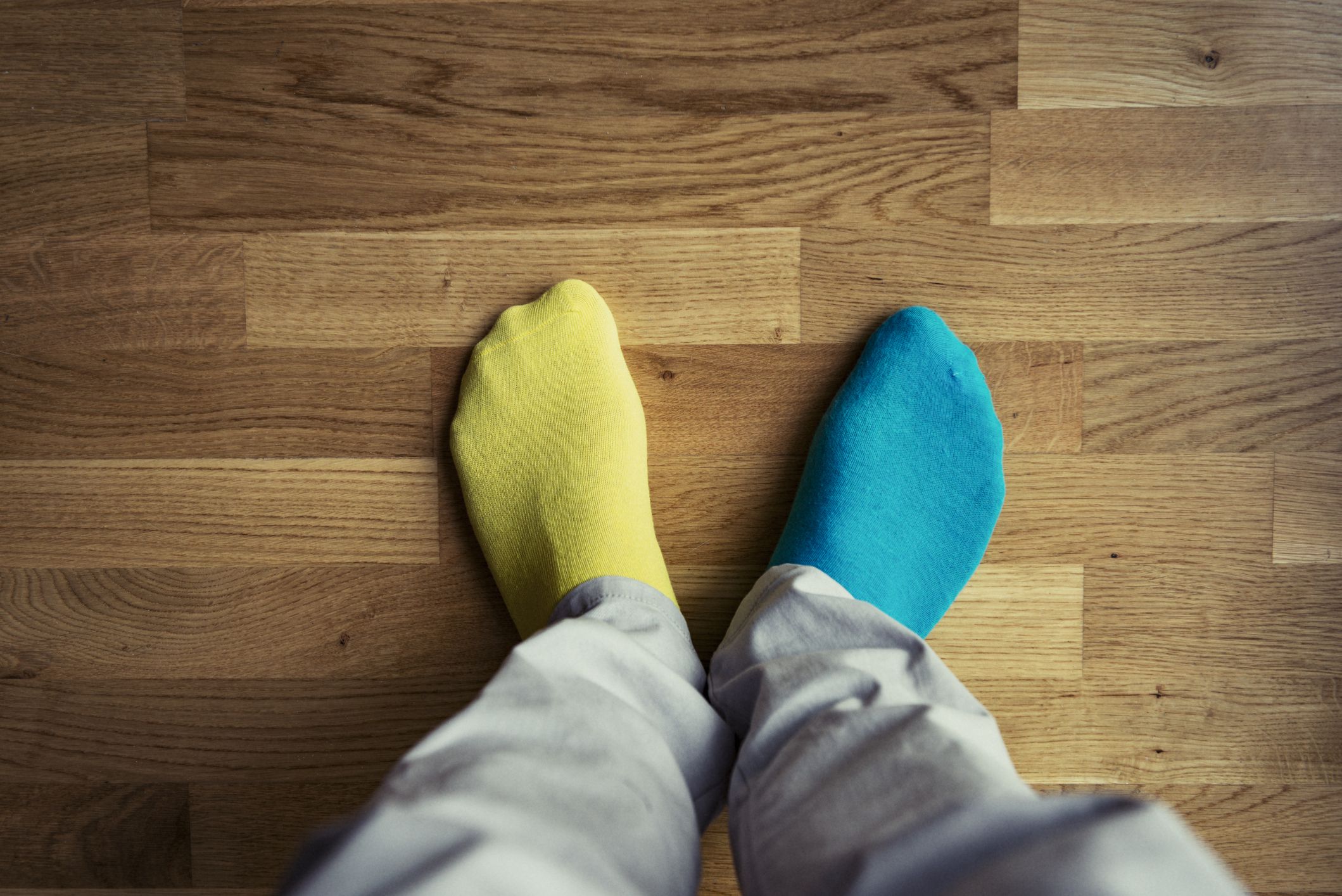 View of mans feet wearing mis matched coloured socks.