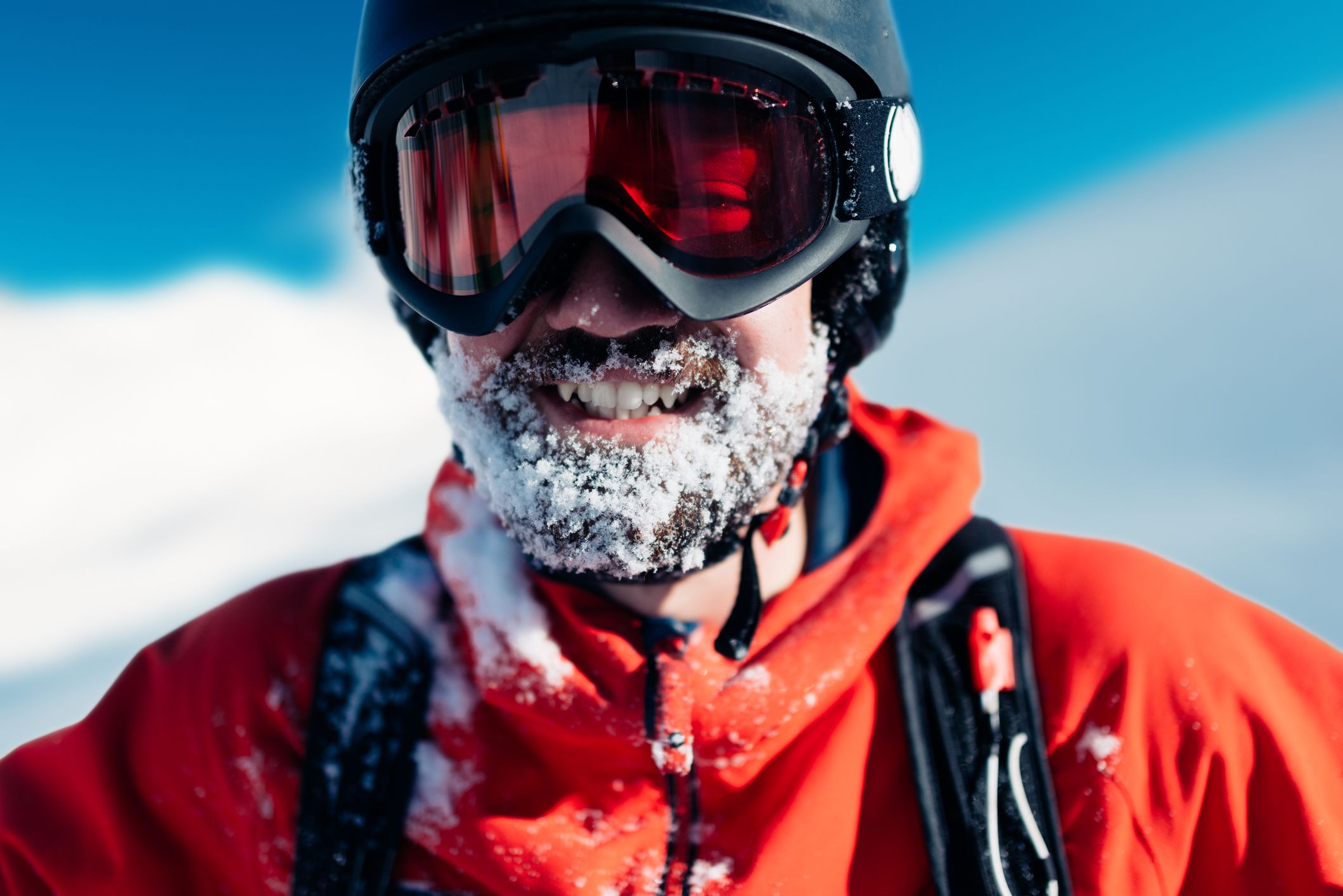 happy snowboarder is standing in the red suit on the snow powder hill and smiling
