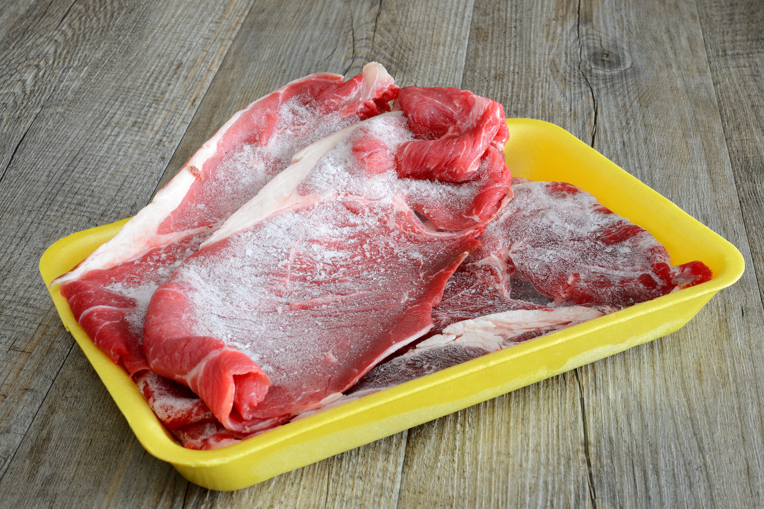 Frozen meat sitting on a wooden surface