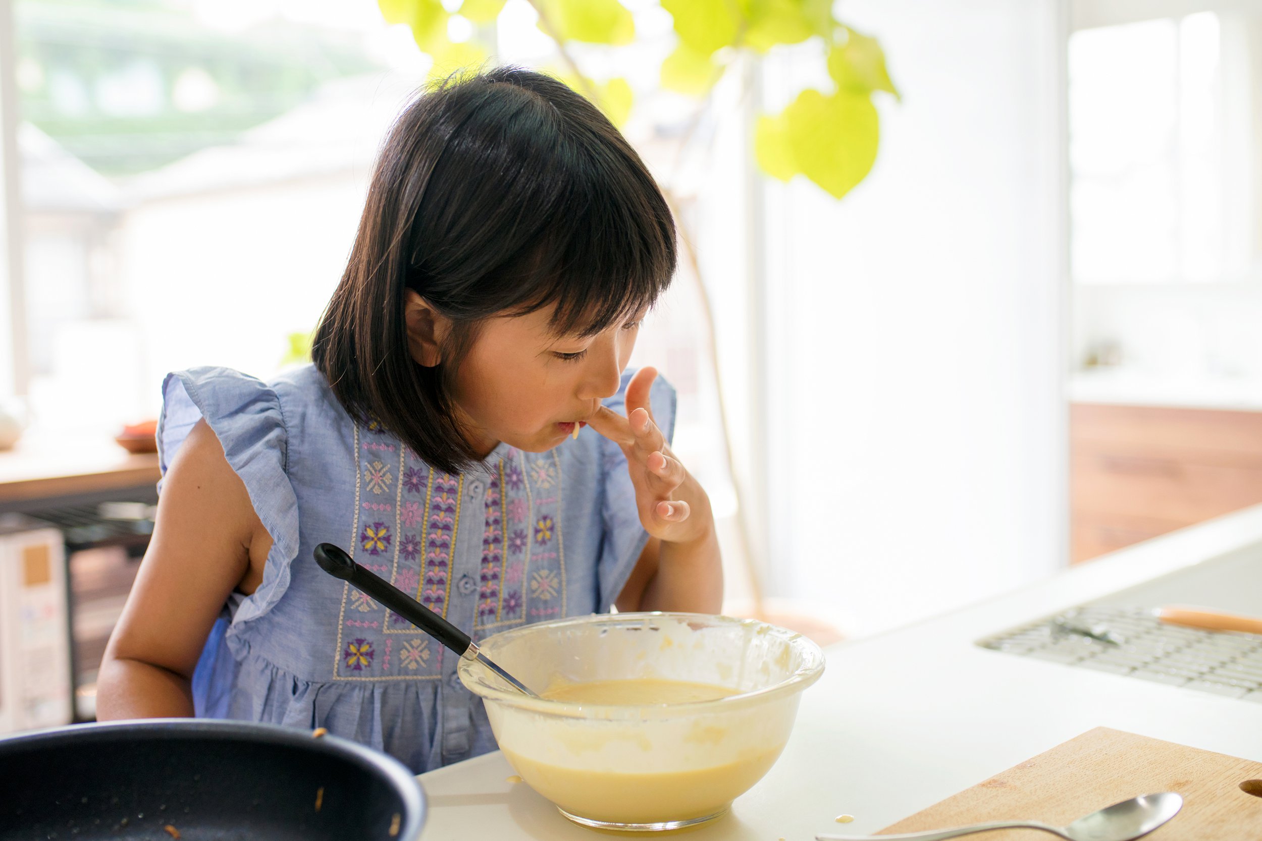 Little girl tasting raw batter