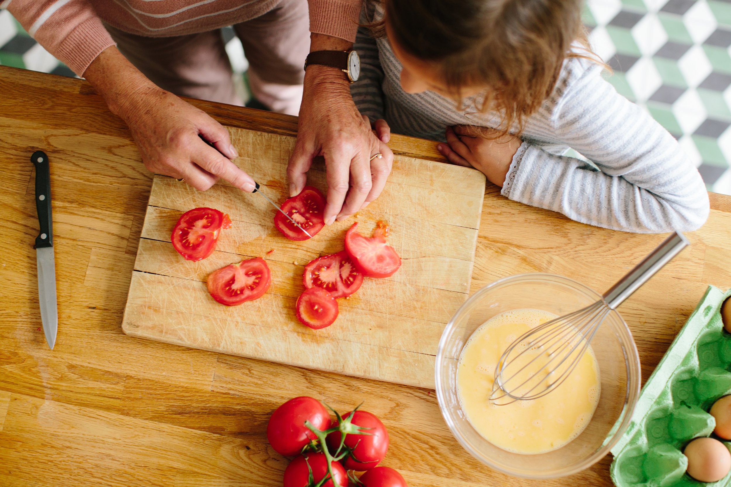 Mother slicing tomatoes in the kitchen with her daughter