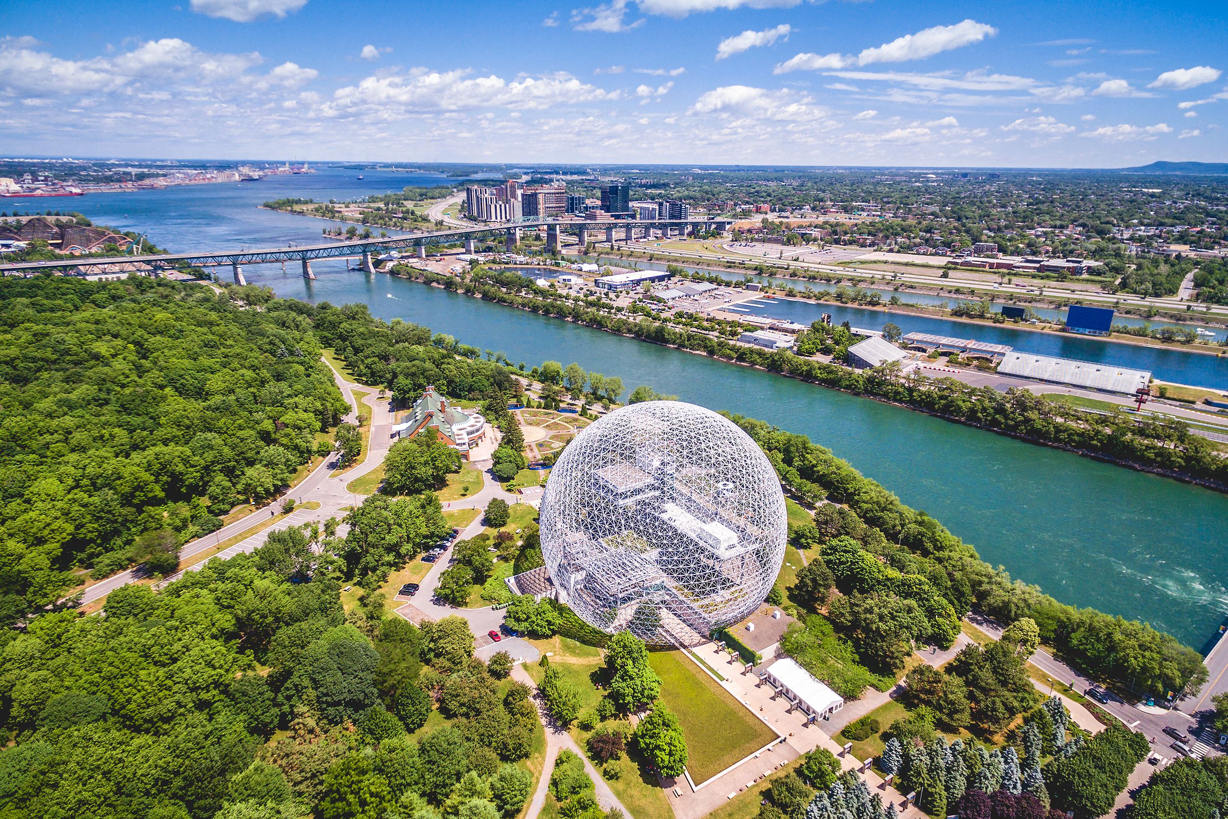Aerial of Montreal, Canada showcasing expansive view of river and downtown on a sunny day during summer