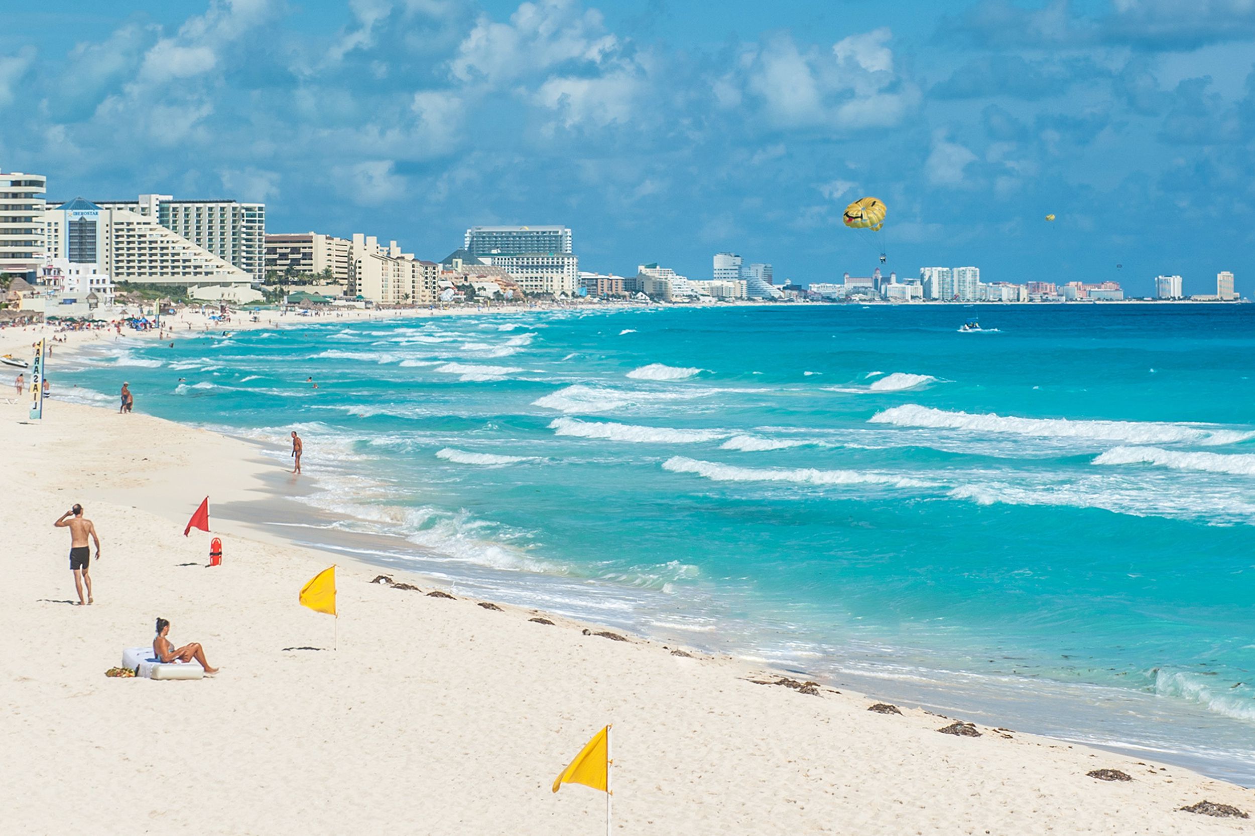 Beach and ocean of Cancun, Mexico with people and buildings on a sunny and windy day