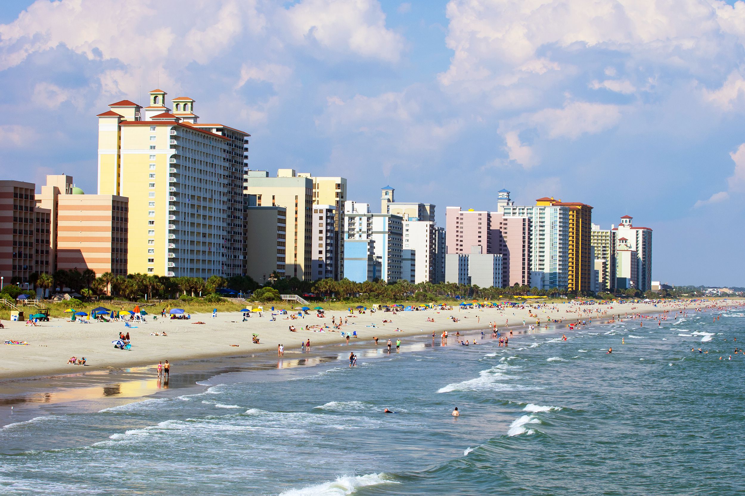 Beach of Myrtle Beach, South Carolina with people and buildings during a cloudy and sunny day
