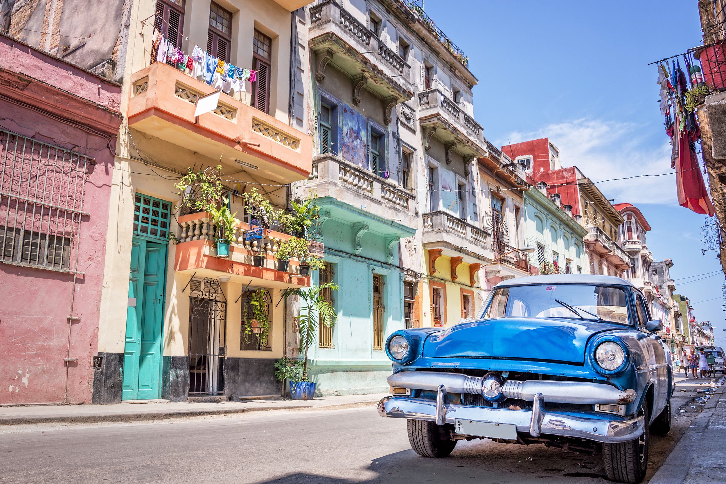 Focus on blue vintage classic American car parked on a road lined with colorful buildings in Havana, Cuba on a sunny day