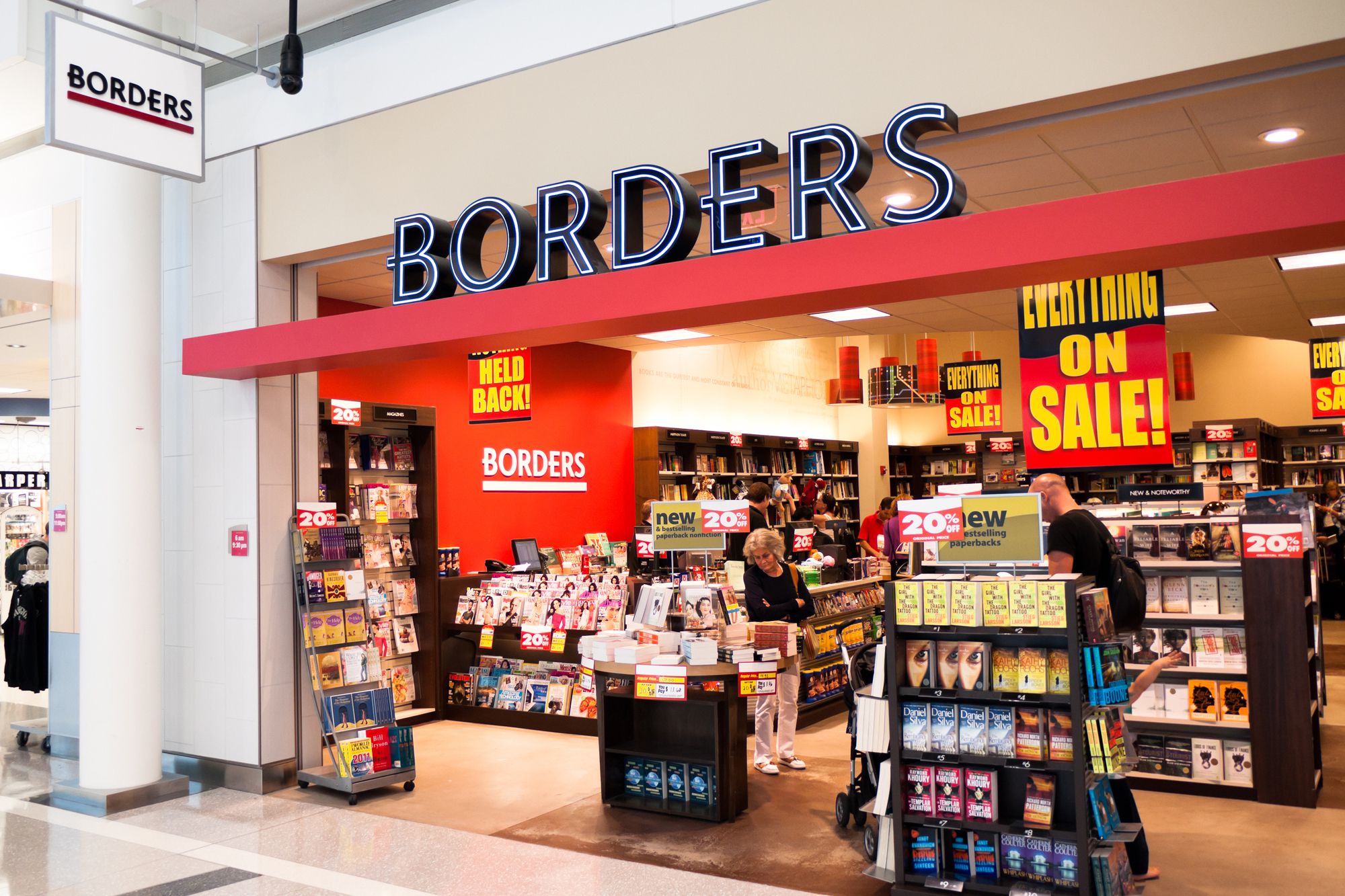Borders Books storefront in a mall, Chantilly, Virginia with several store closing signs hung inside, a few people looking at books in store