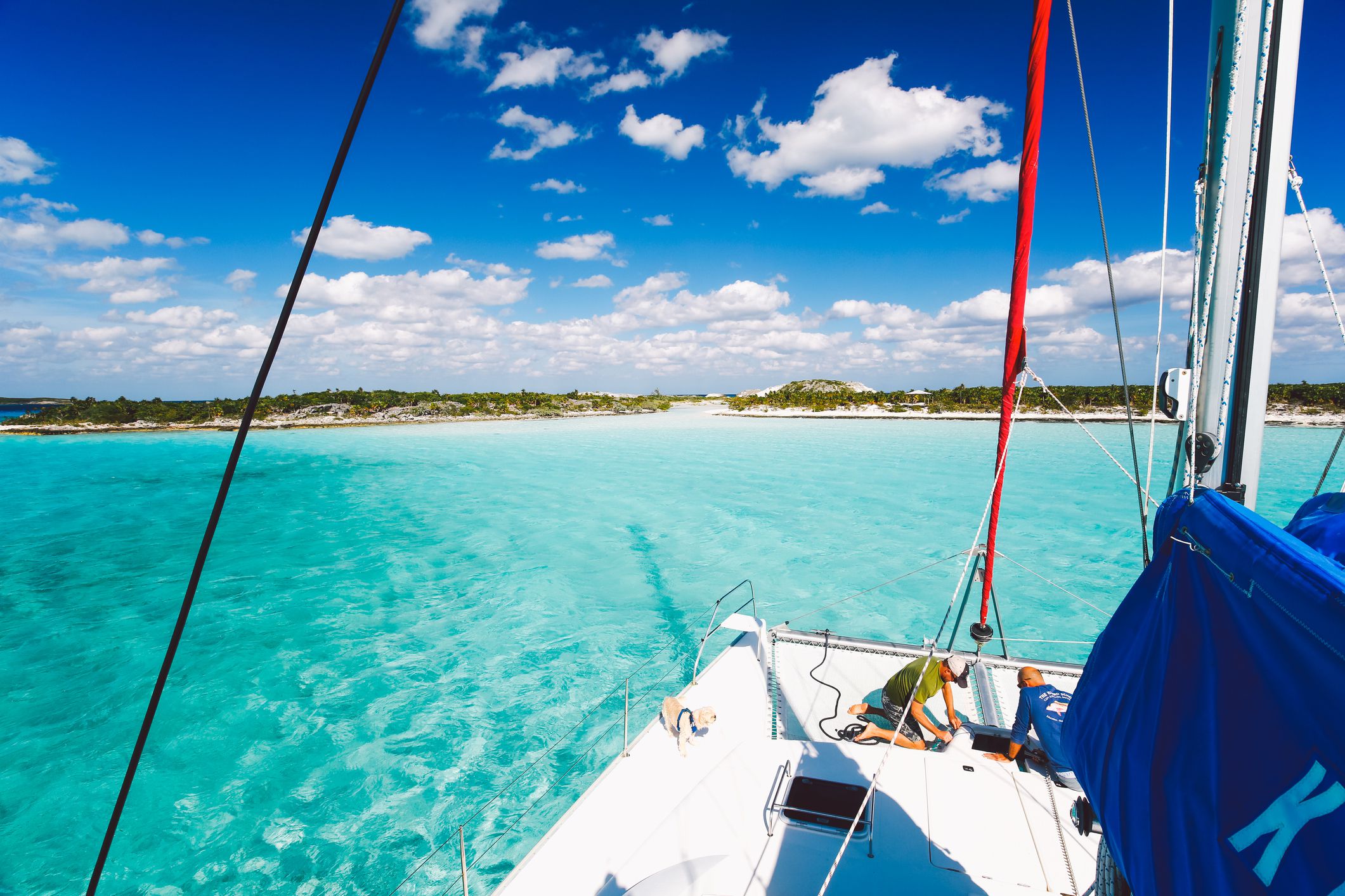 Calm and shallow turquoise ocean and beach on an island of Exumas archipelago in the Bahamas as seen from a small sail boat on a sunny day
