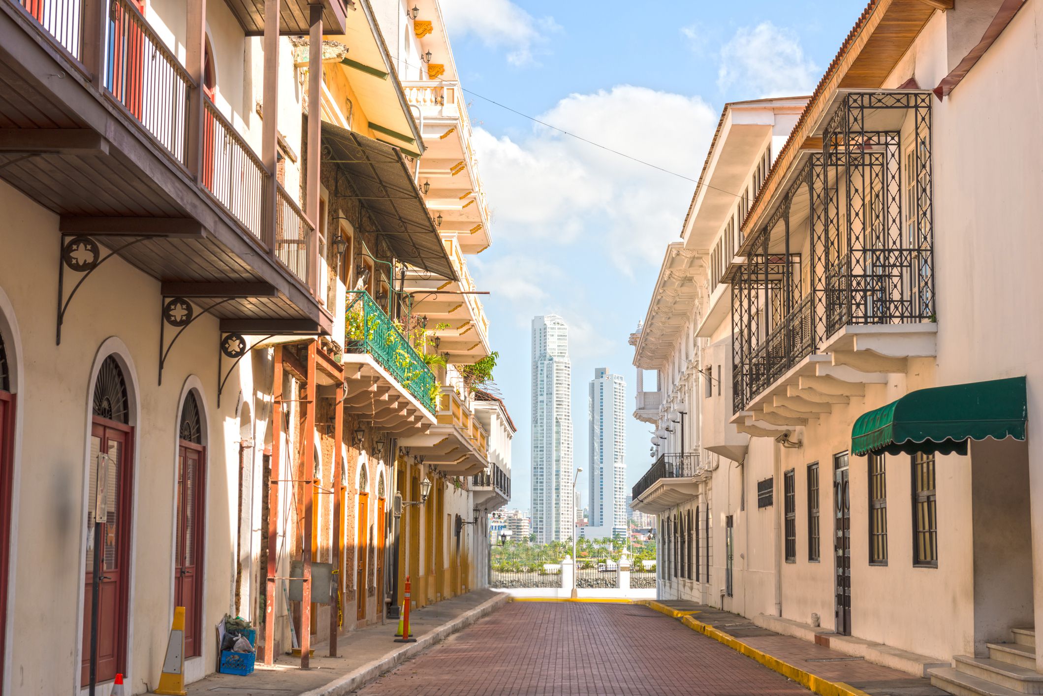 Casco Viejo street in an old part of Panama City, Panama with view of modern downtown skyscrapers in the distance, sandwiched in between two sides of the street