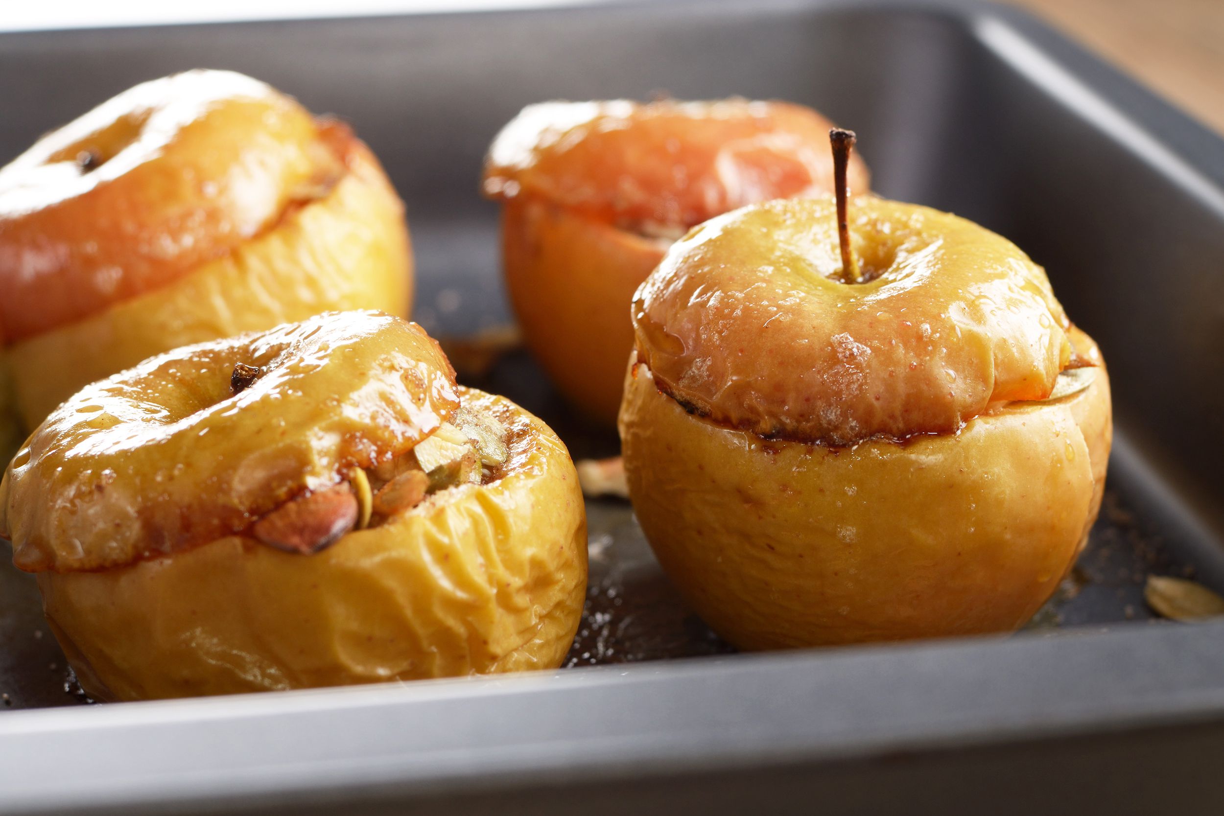 Closeup of four baked apples in a baking pan with a blurred background
