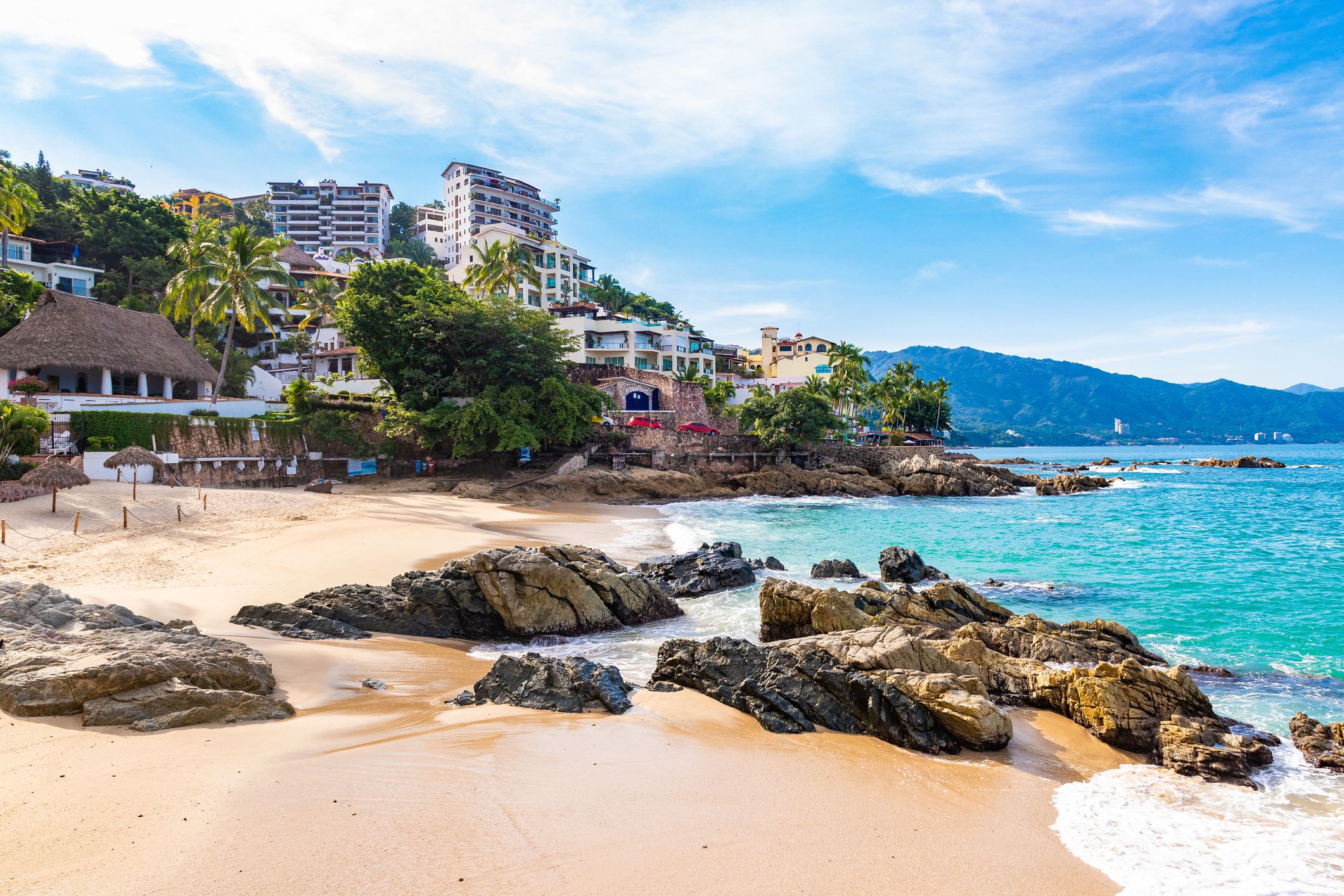 Empty Conchas Chinas Beach, Puerto Vallarta, Mexico during morning on a sunny day with mountains in the background