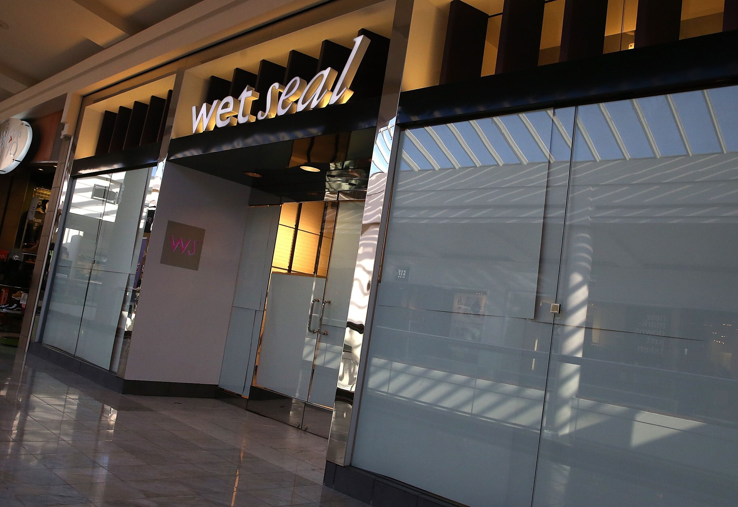 Exterior of closed Wet Seal, San Francisco with windows and front doors completely covered with paper, inside a mall