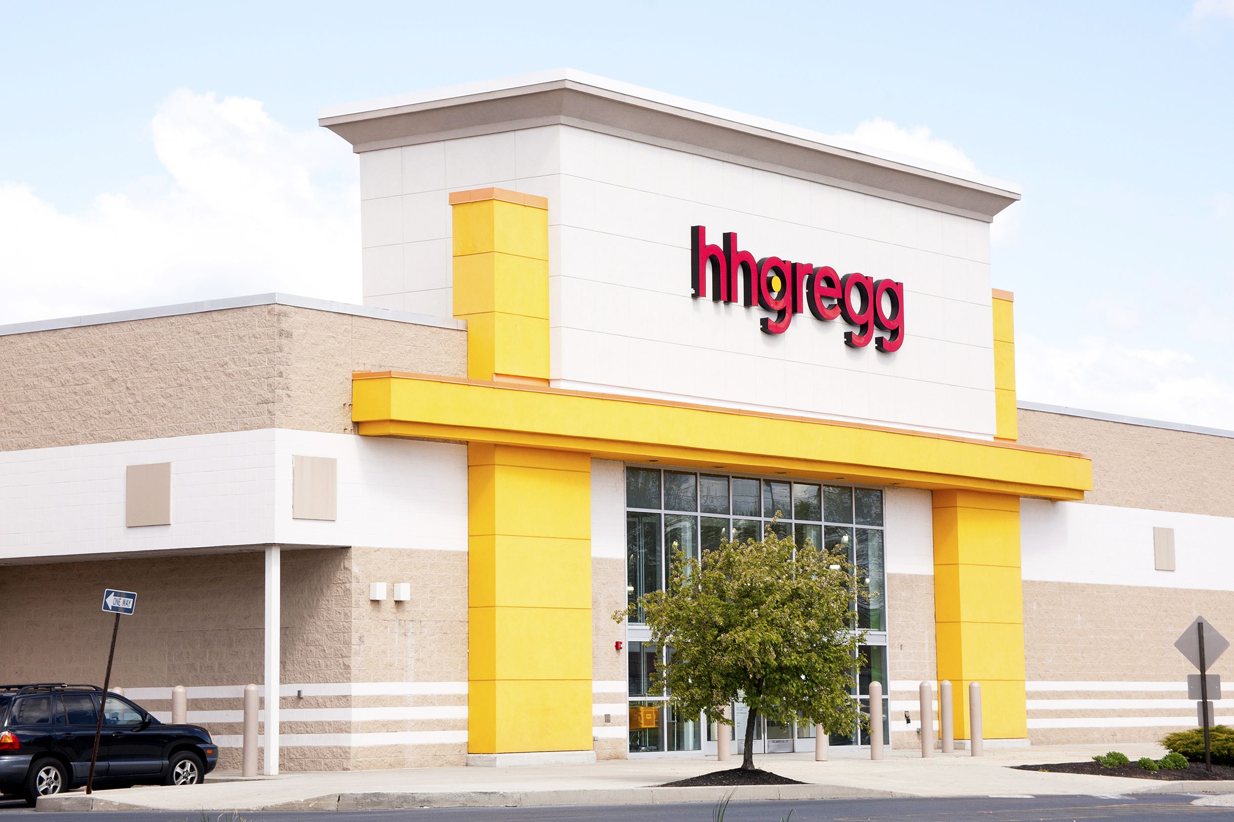 Front exterior and side of hhgregg store, Mechanicsburg, Pennsylvania, very clean building and sidewalk with a car parked along the side, on a spring day