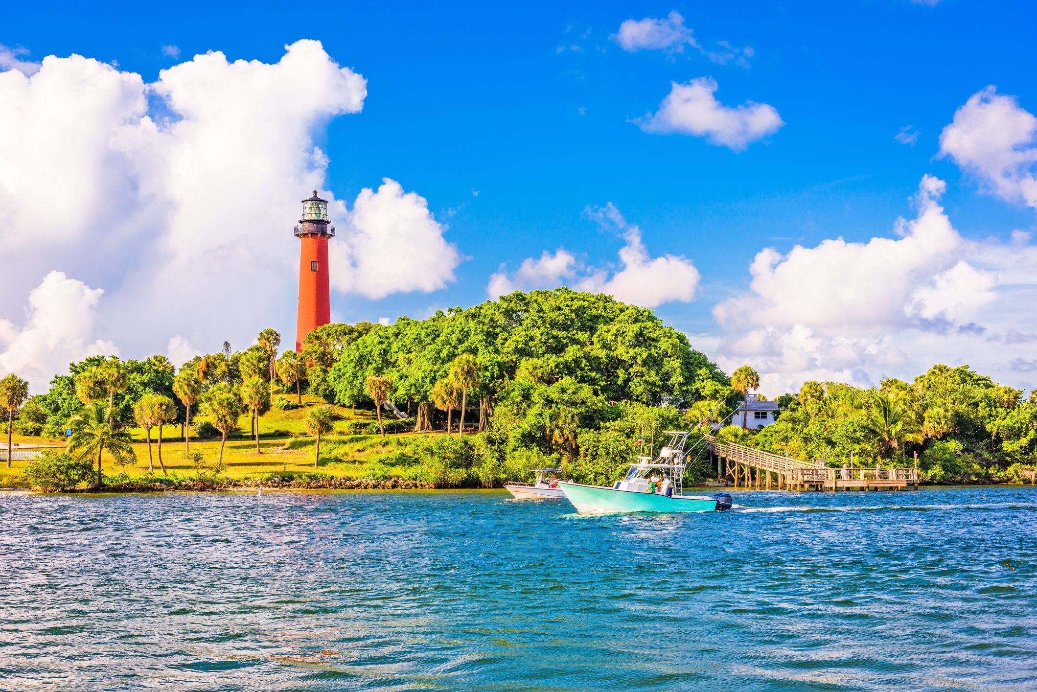 Inlet with two boats and light house in Jupiter, Florida on a sunny day