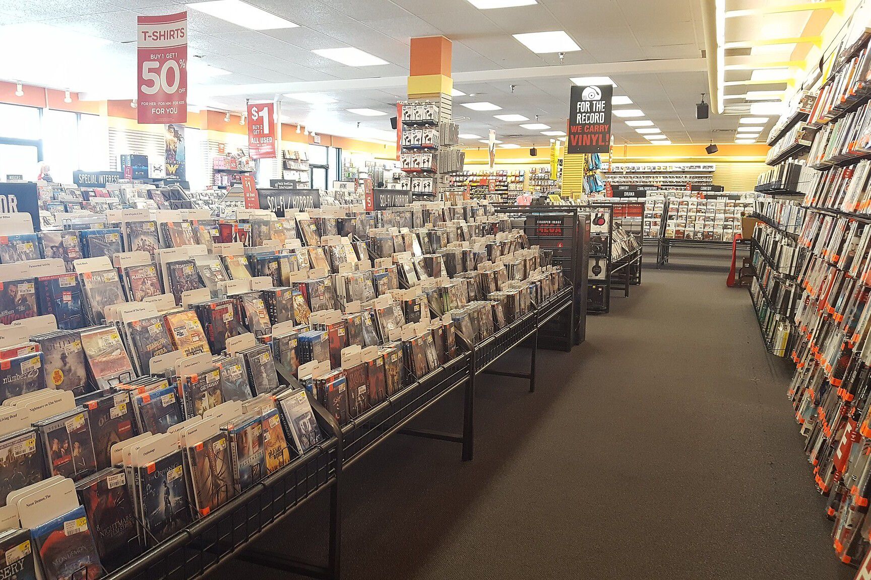 Interior of Sam Goody store, Cookeville, Tennessee, focus on dvd aisle of Sci-Fi/Horror DVDs for sale on the left with another aisle of DVDs along the wall on the right, many other rows of DVDs and CDs in the store, 2017