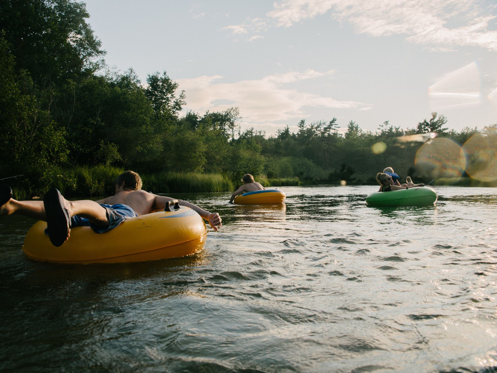 Young people floating down river in inner tubes