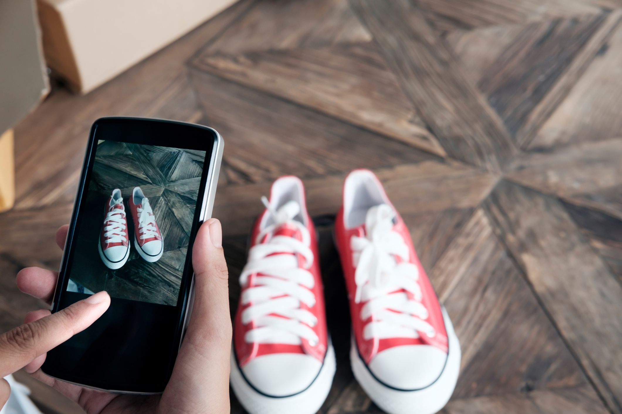 Mobile phone taking photo of red and white sneakers