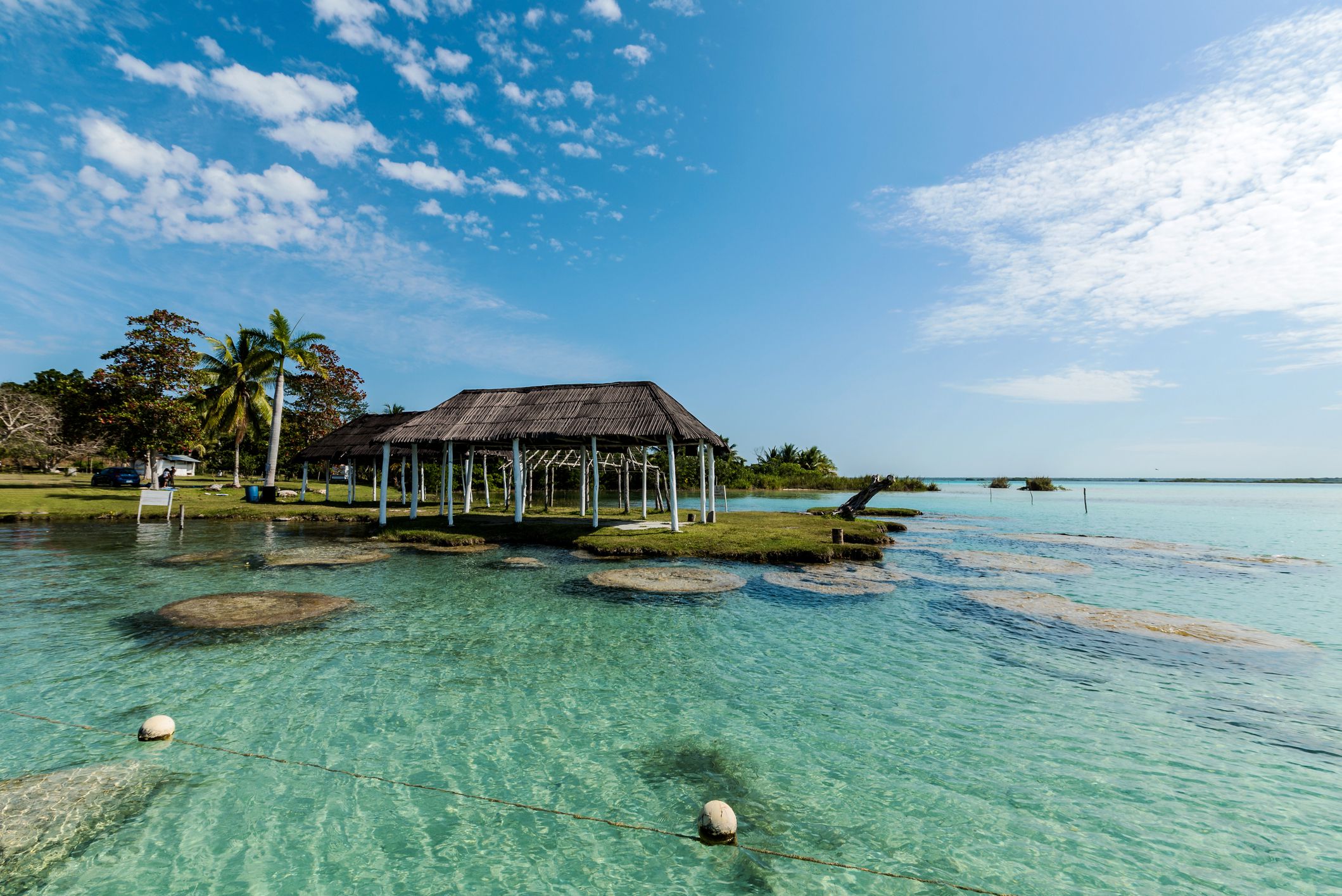 Shallow coral waters and pavilion in Laguna Bacalar, Mexico with expansive view of waters and blue sky