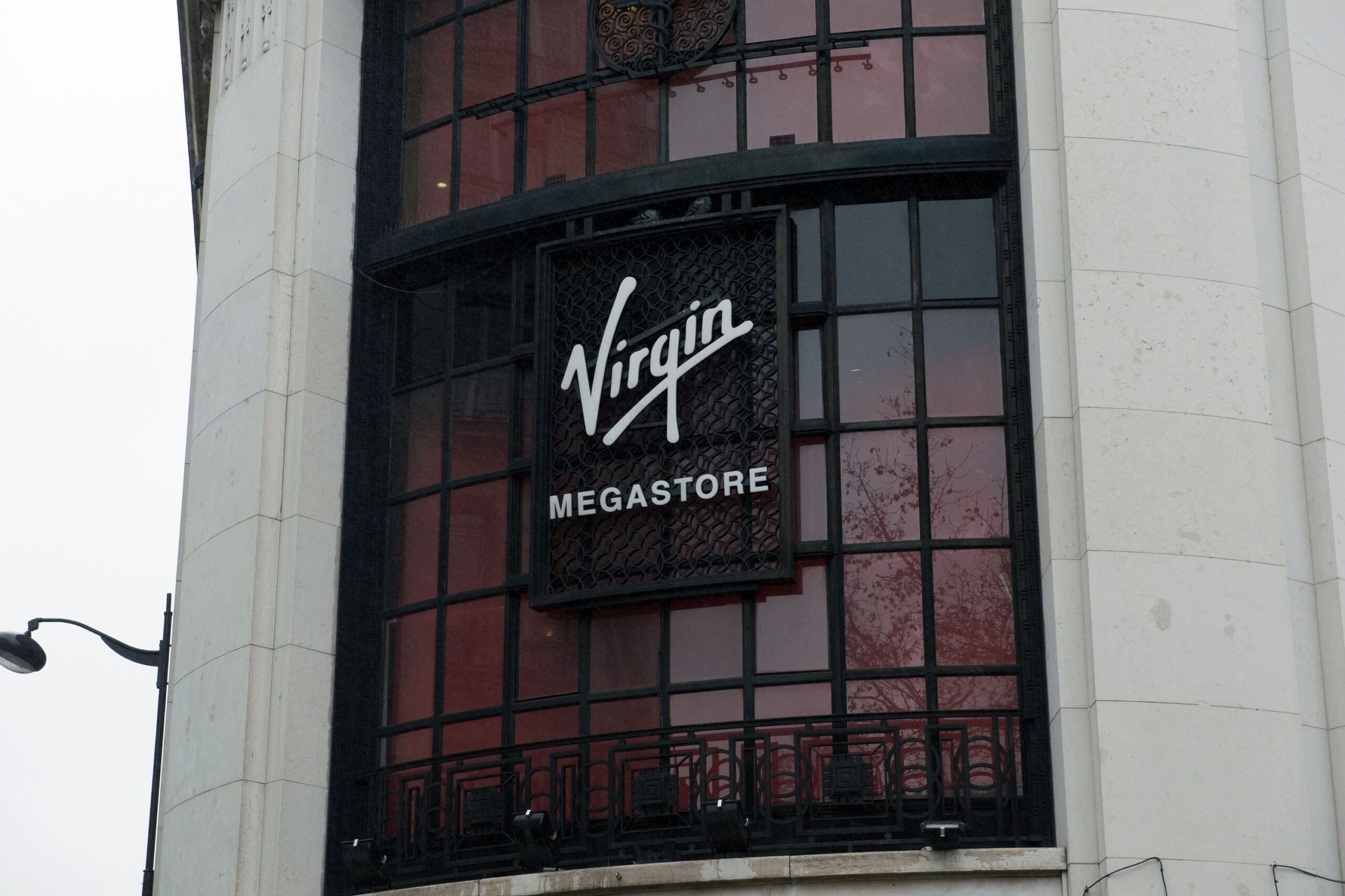 Front exterior of sign on windows of Virgin Megastore on the Champs Elysées, Paris, white stone building with a grey sky
