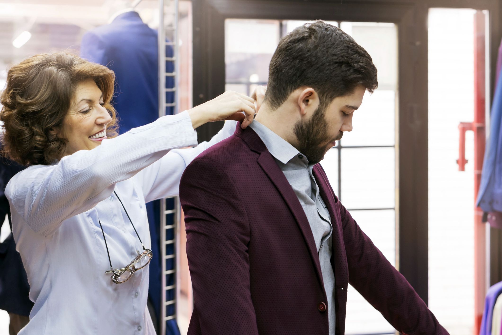 woman helping young man adjust jacket
