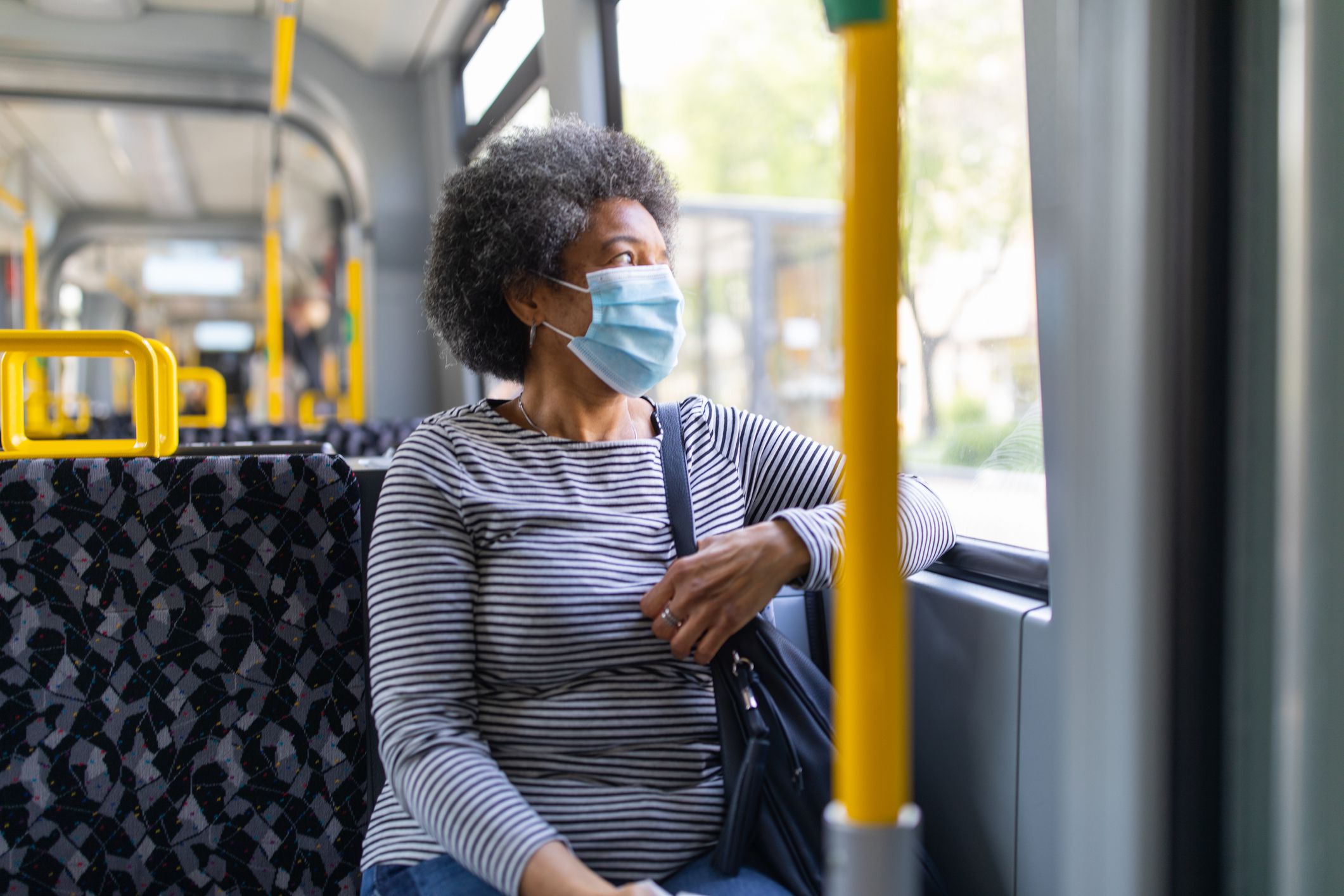 Woman wearing medical face mask commuting in a tram train during corona virus outbreak. Female travelling in metro during Covid-19 pandemic.
