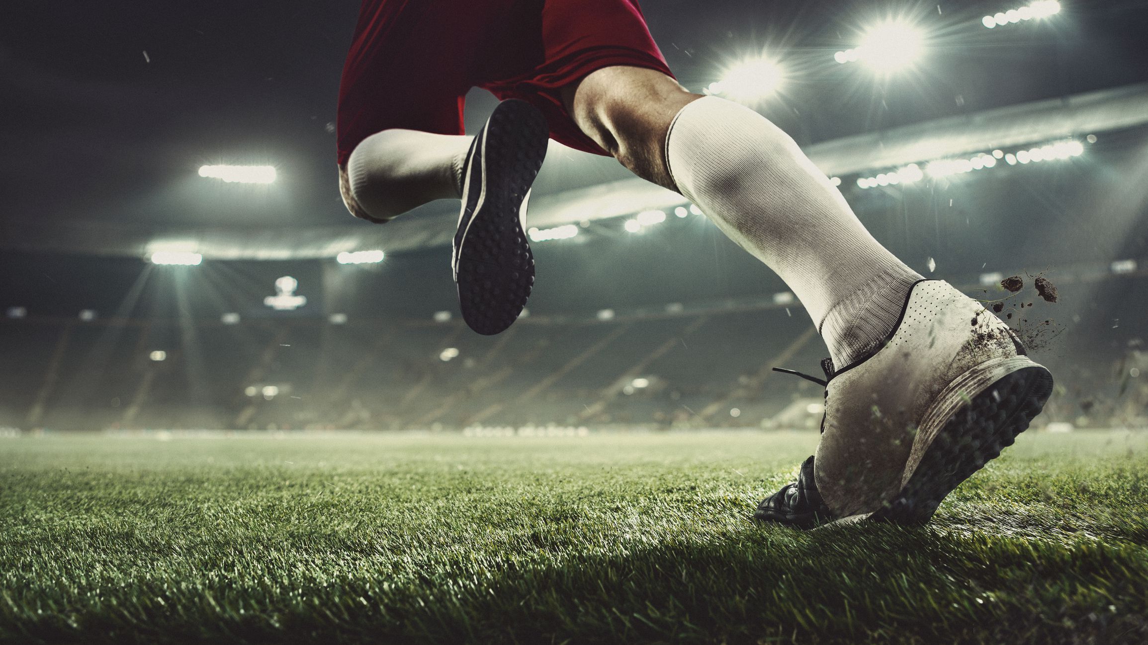 Leader. Close up football player at stadium in flashlight. Young sportsman during the match. Moment of attacking, catching. Concept of sport, competition, winning, action, motion, overcoming.