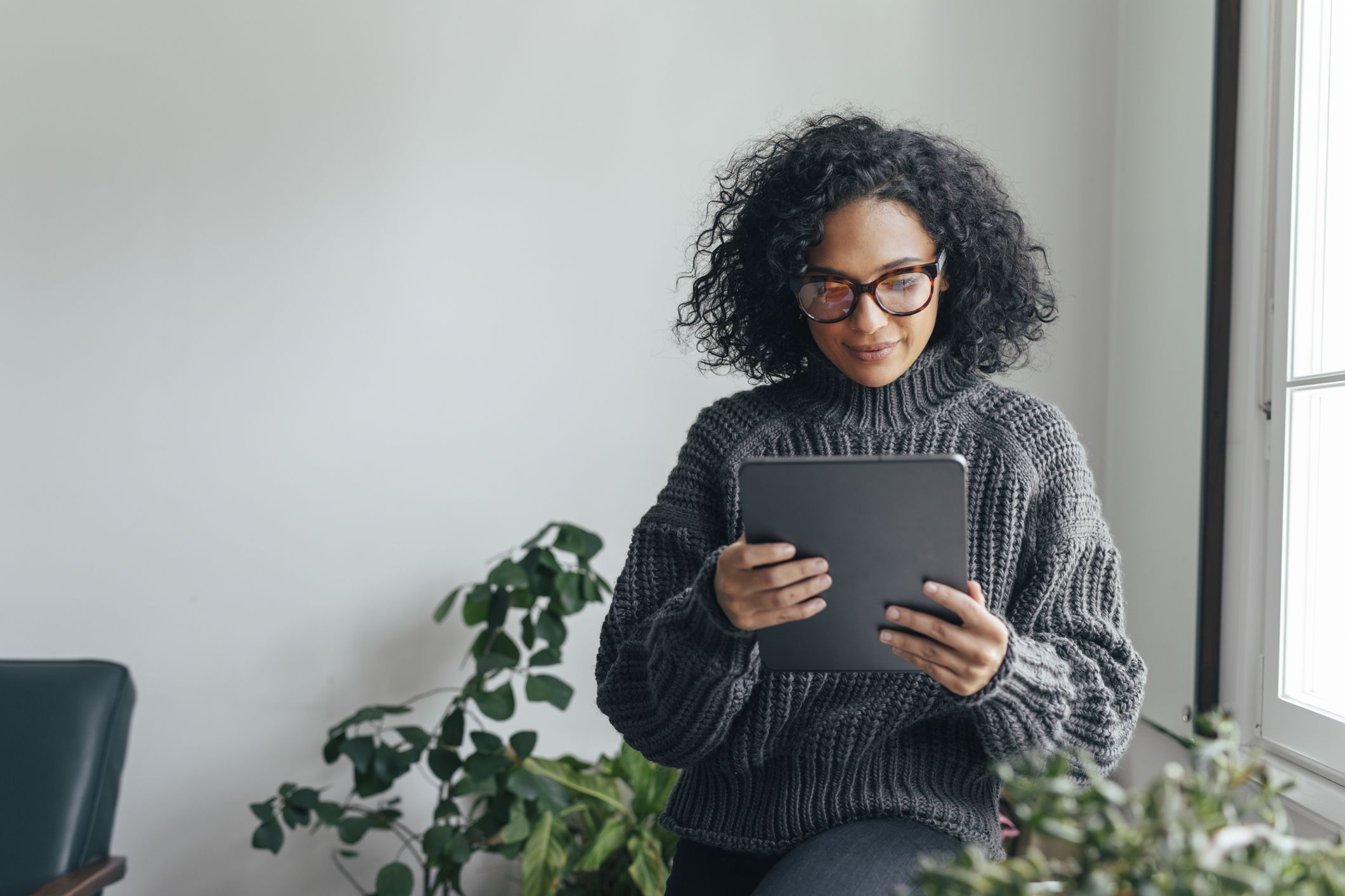 Young woman wearing glasses watching something on her digital tablet (copy space).