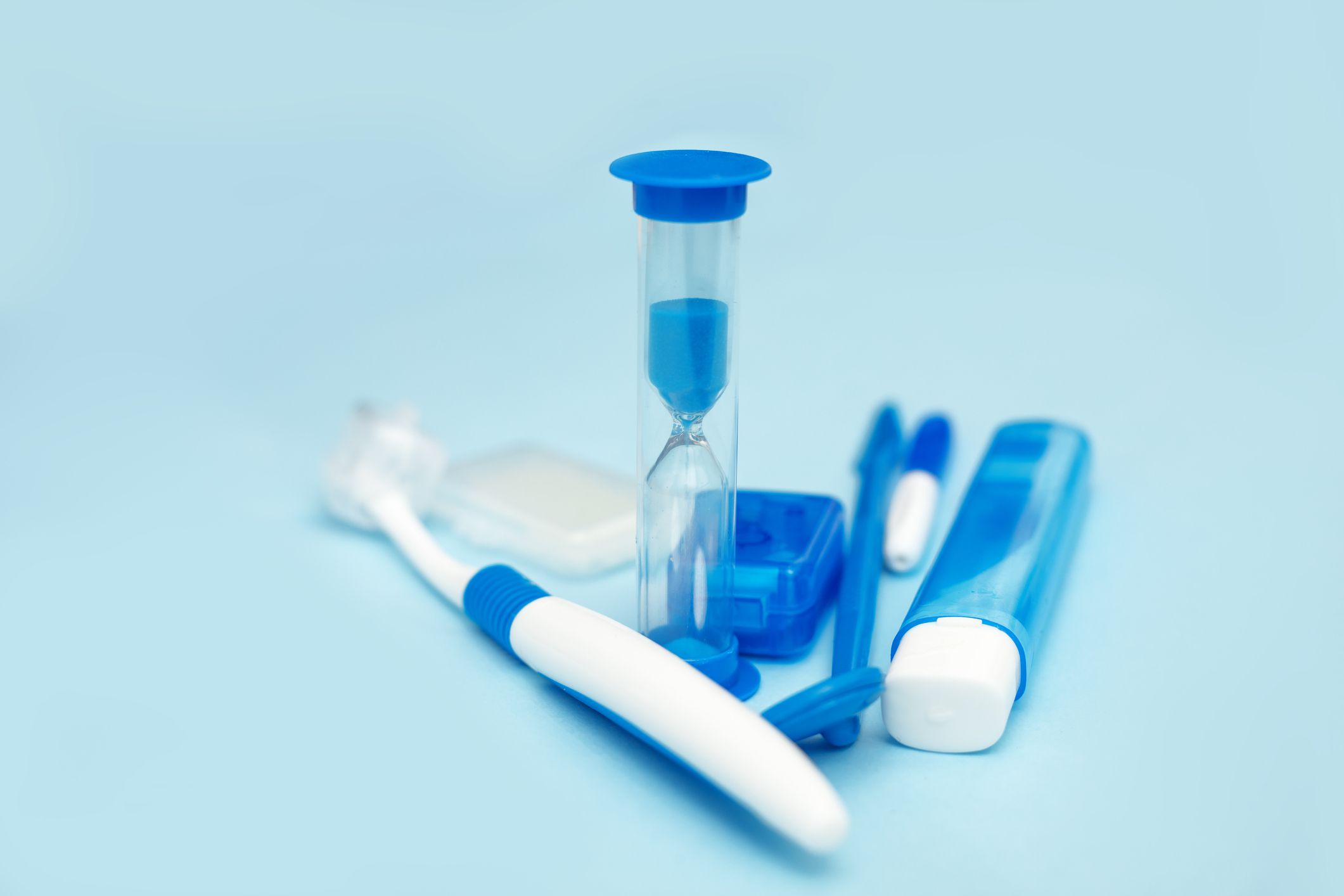 Oral hygiene while wearing braces, braces, home care kit, dental instruments, dental floss, toothbrushes, hourglass. Dental concept on a blue background. Front View photo