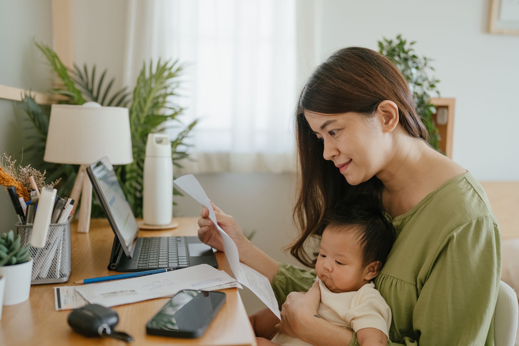 Woman holding paper various expense bills and plans for personal finances at her home.