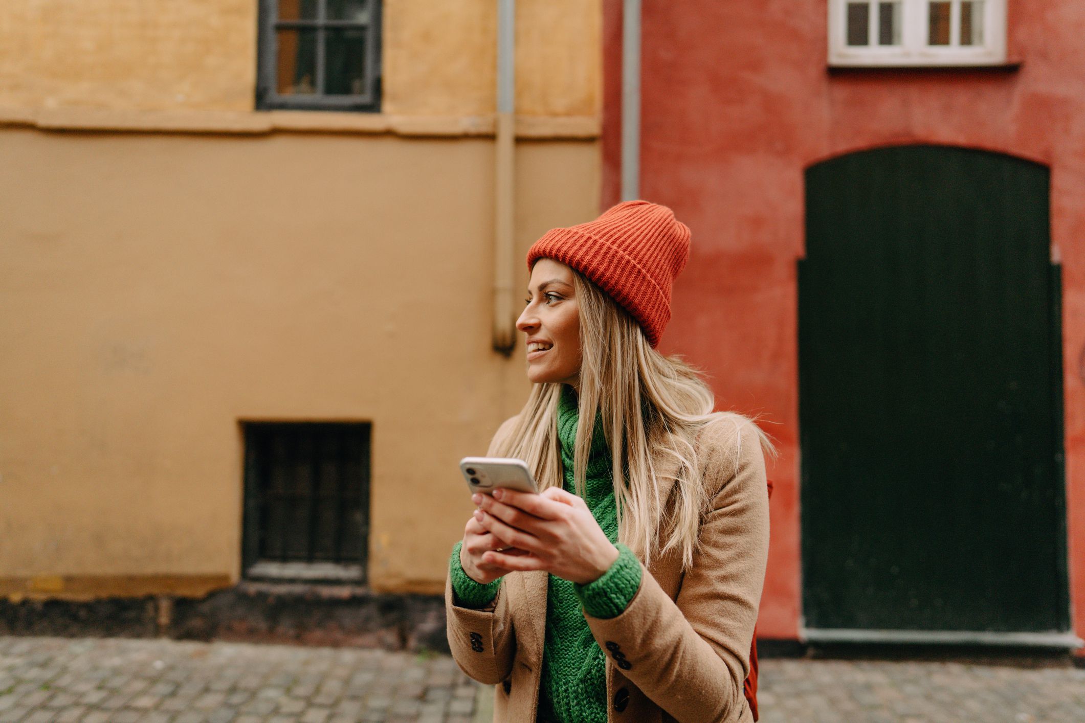 Photo of a young woman using maps app on her mobile phone while travelling and looking for right direction