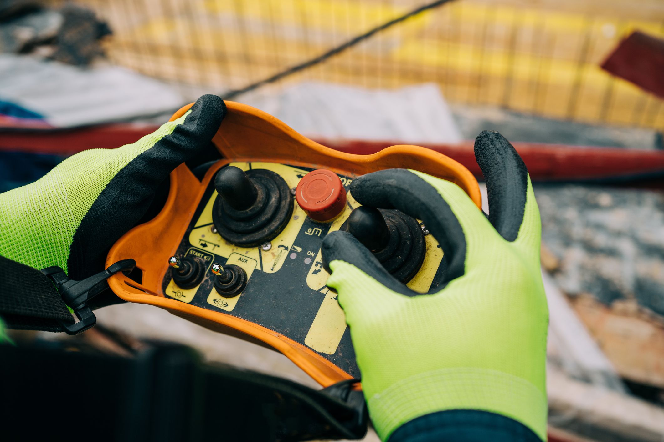 Unrecognizable construction worker/operator is holding industrial remote wireless console to control overhead crane with joystick at construction site.