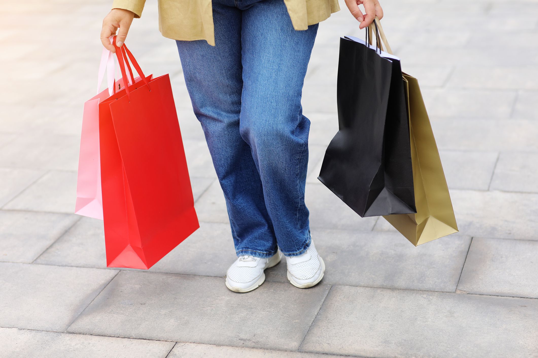 Cropped portrait of unrecognisable woman with colourful shopping bags on urban shopping mall background. Purchases, black friday, discounts, sale concept. Online shopping concept, Seasonal Sales