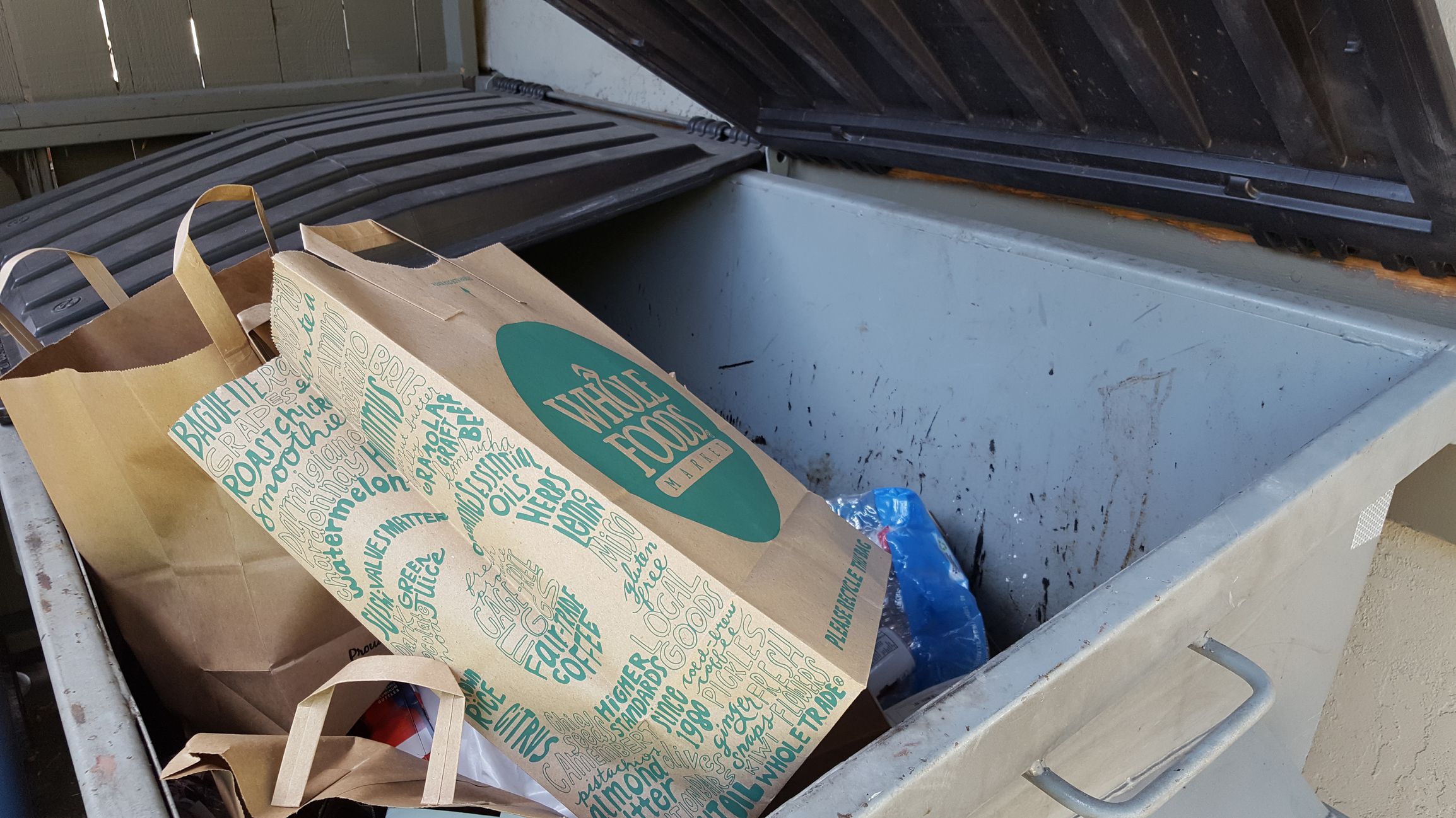 Walnut Creek, United States - September 21, 2016: Several paper shopping bags from Whole Foods Market discarded in a dumpster