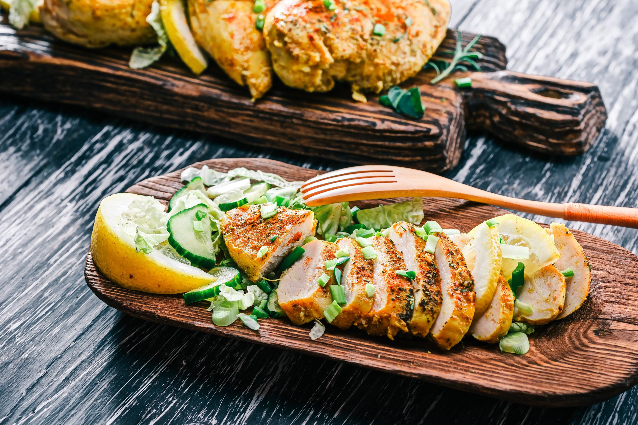 Roasted chicken breasts with green vegetable salad served on rustic wood