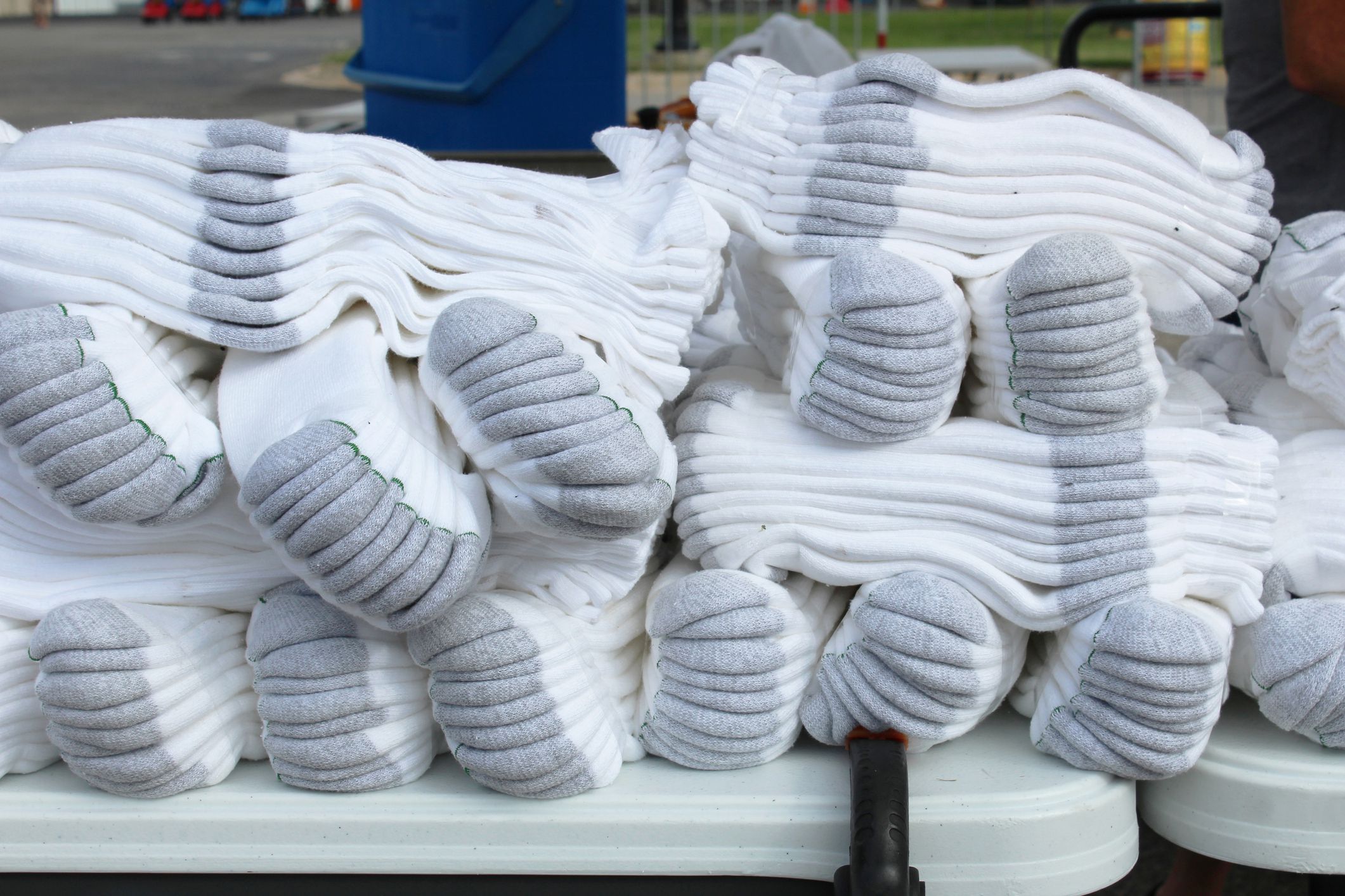 Bundles of white athletic crew socks on a table at an outdoor flea market