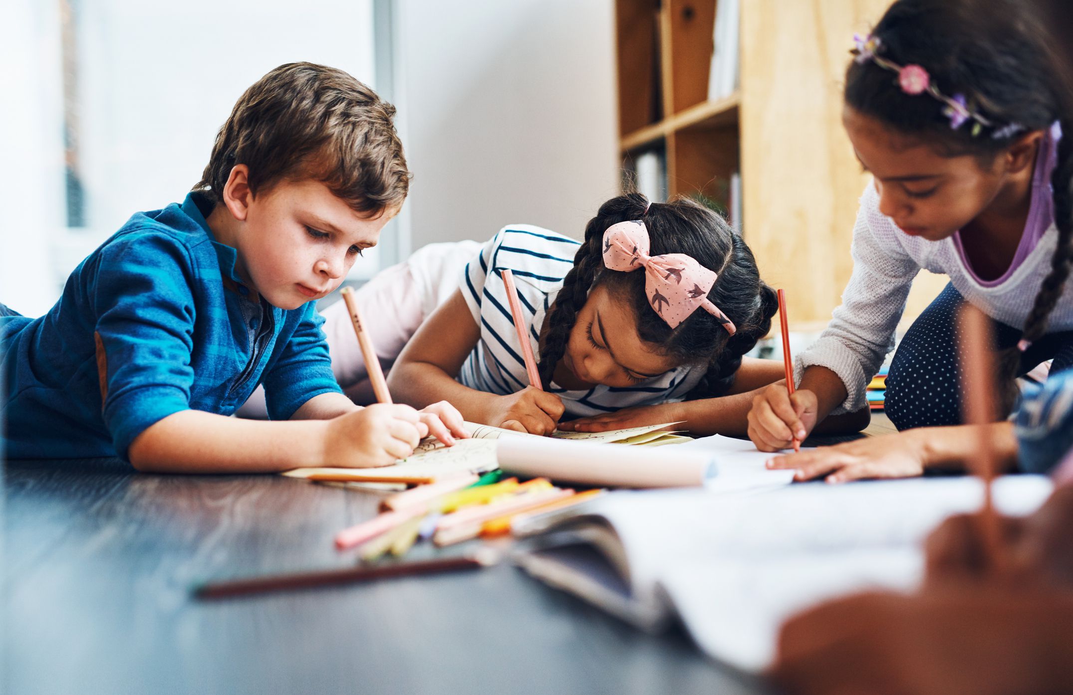 Cropped shot of kids coloring in while lying on the floor