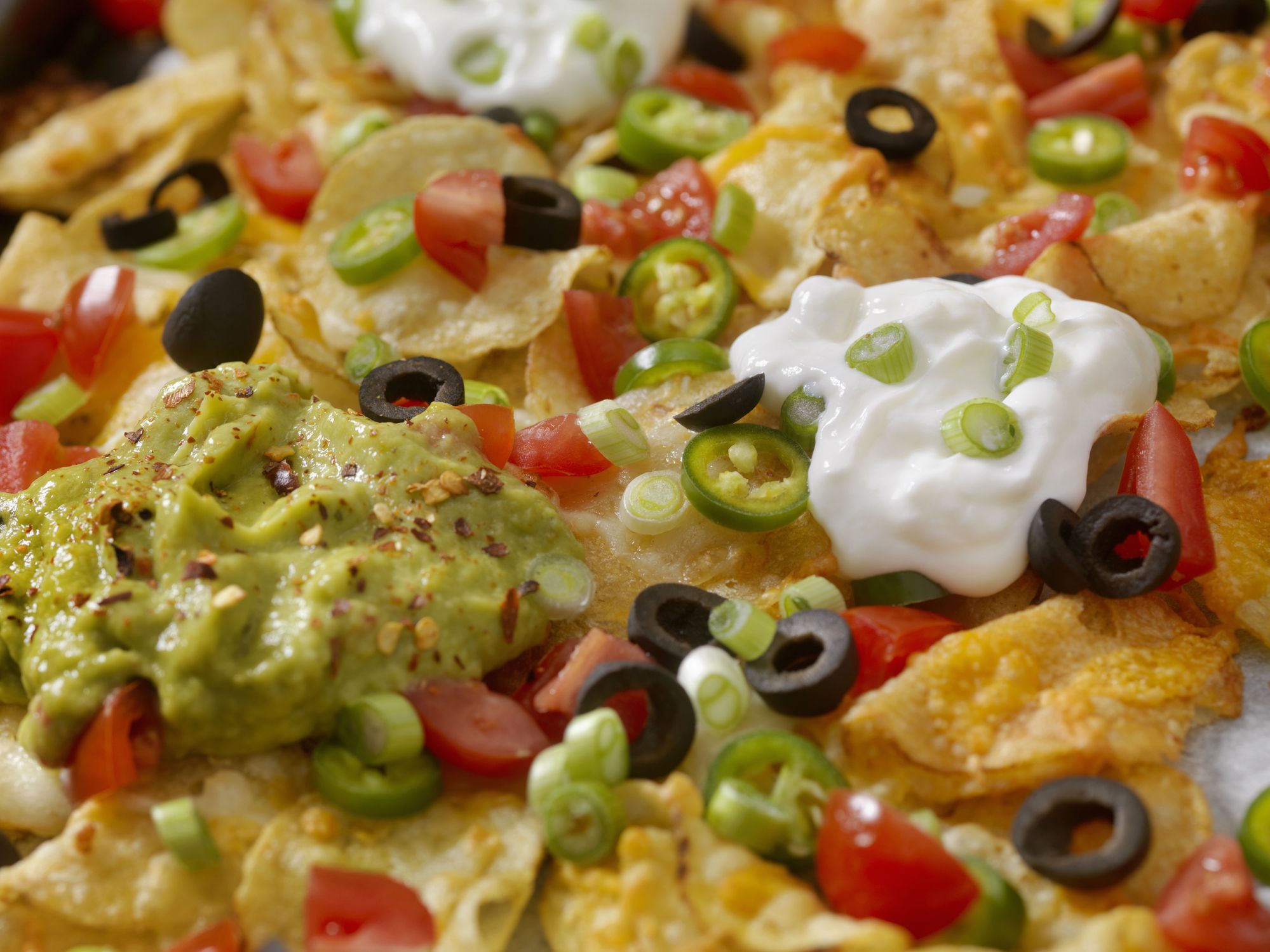 Kettle Cooked Potato Chip Nachos with Black Olives, Tomatoes, Green Onions, Jalapenos, Salsa, Guacamole and Sour Cream