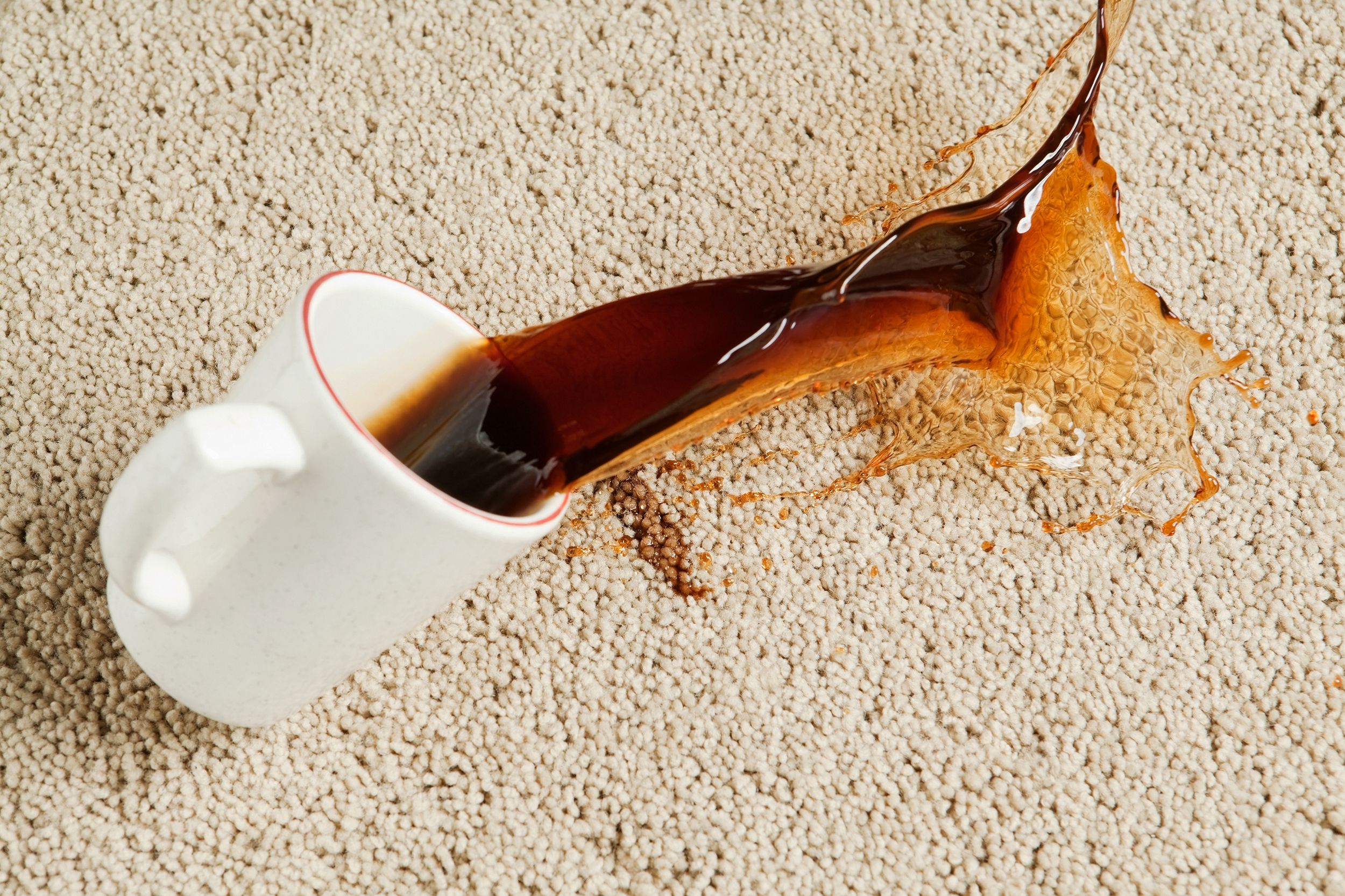 coffee spilling from cup onto carpet