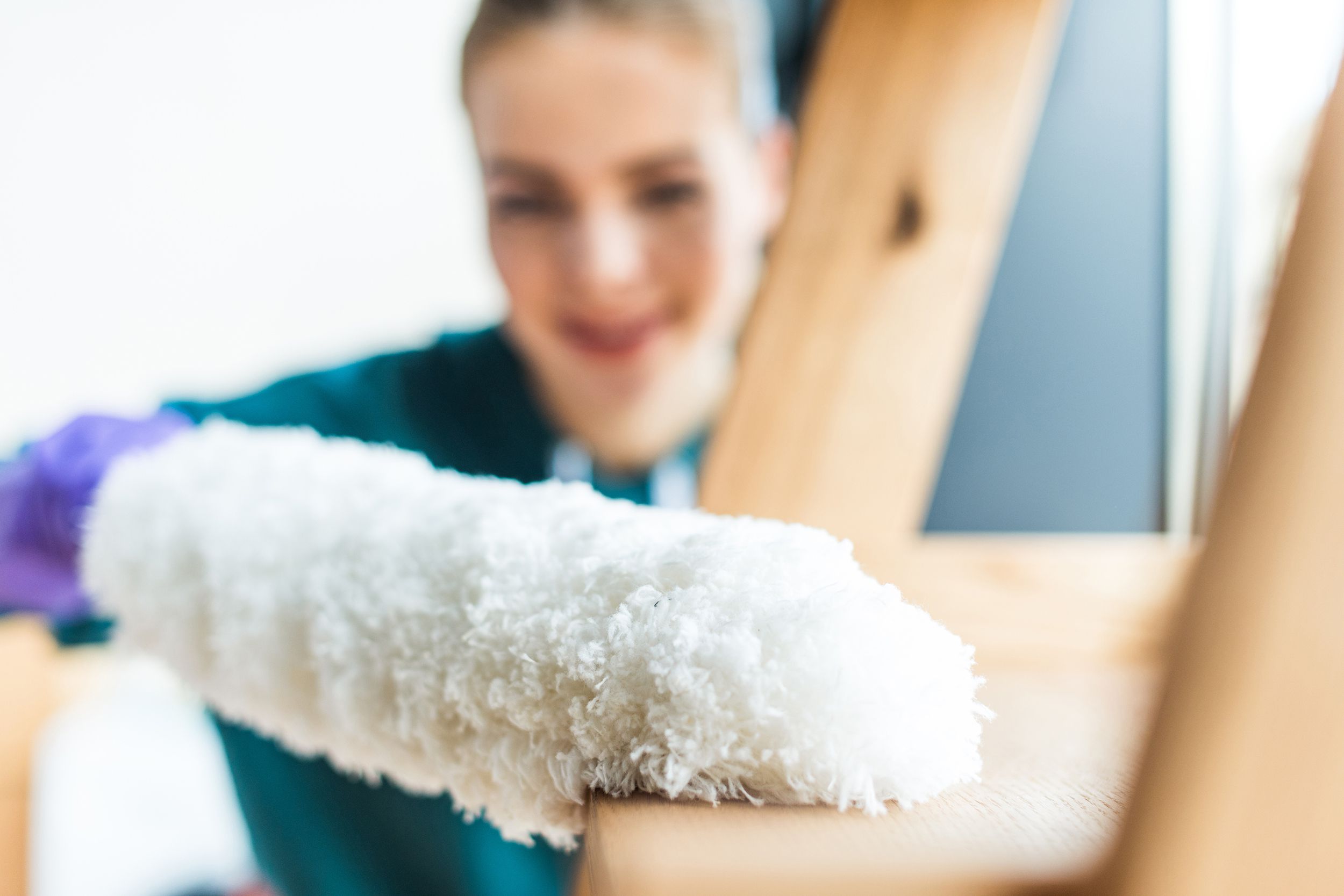 close-up view of young woman with duster cleaning home