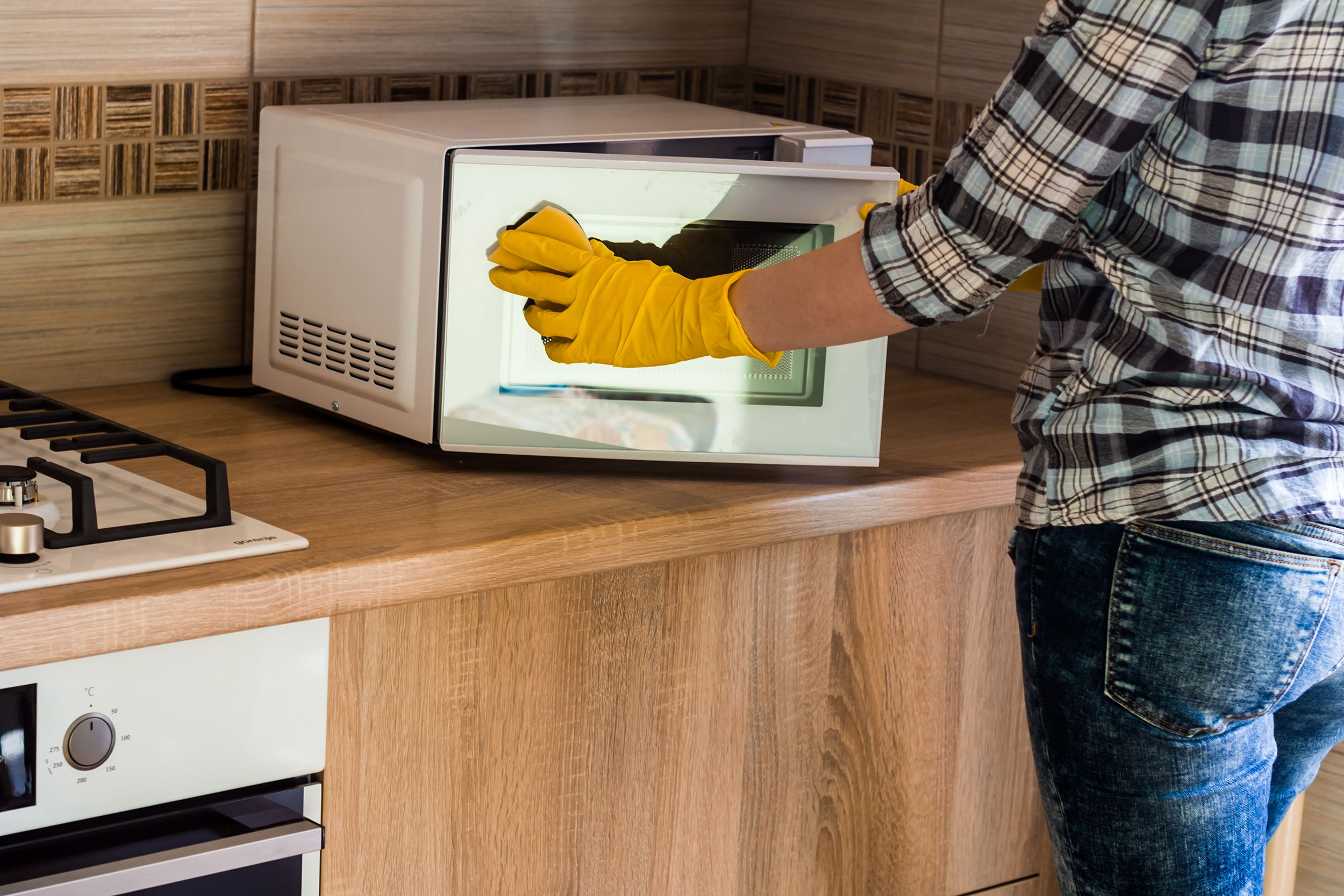 person cleaning microwave with microcloth