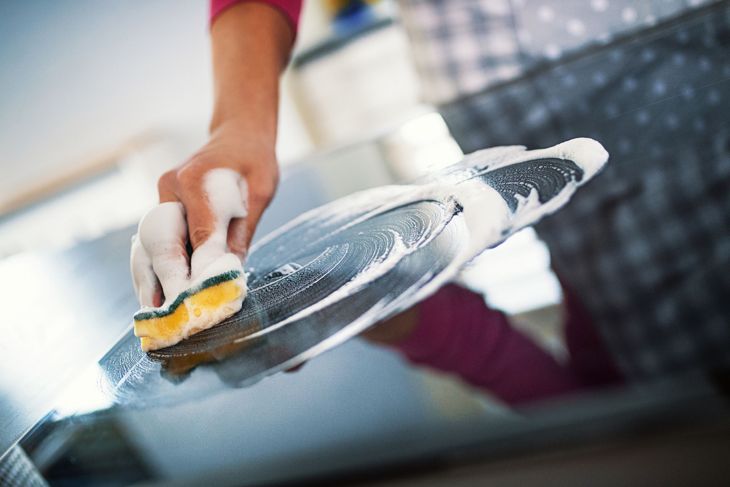 hand with sponge cleaning stone countertop