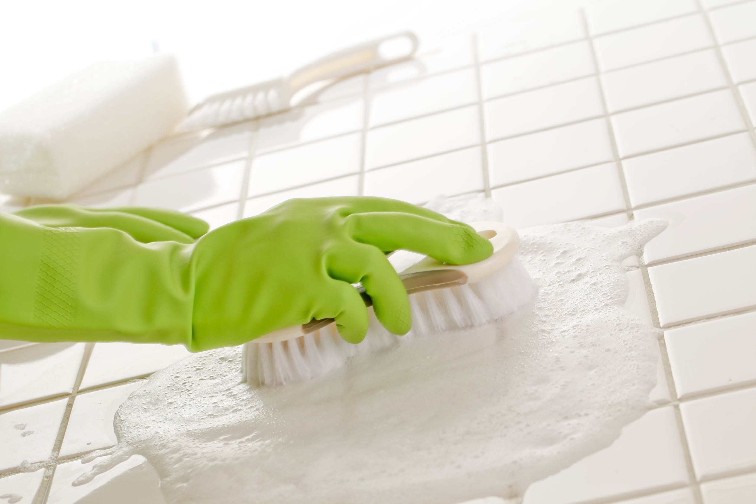 latex gloved hand cleaning floor with cleaning tool