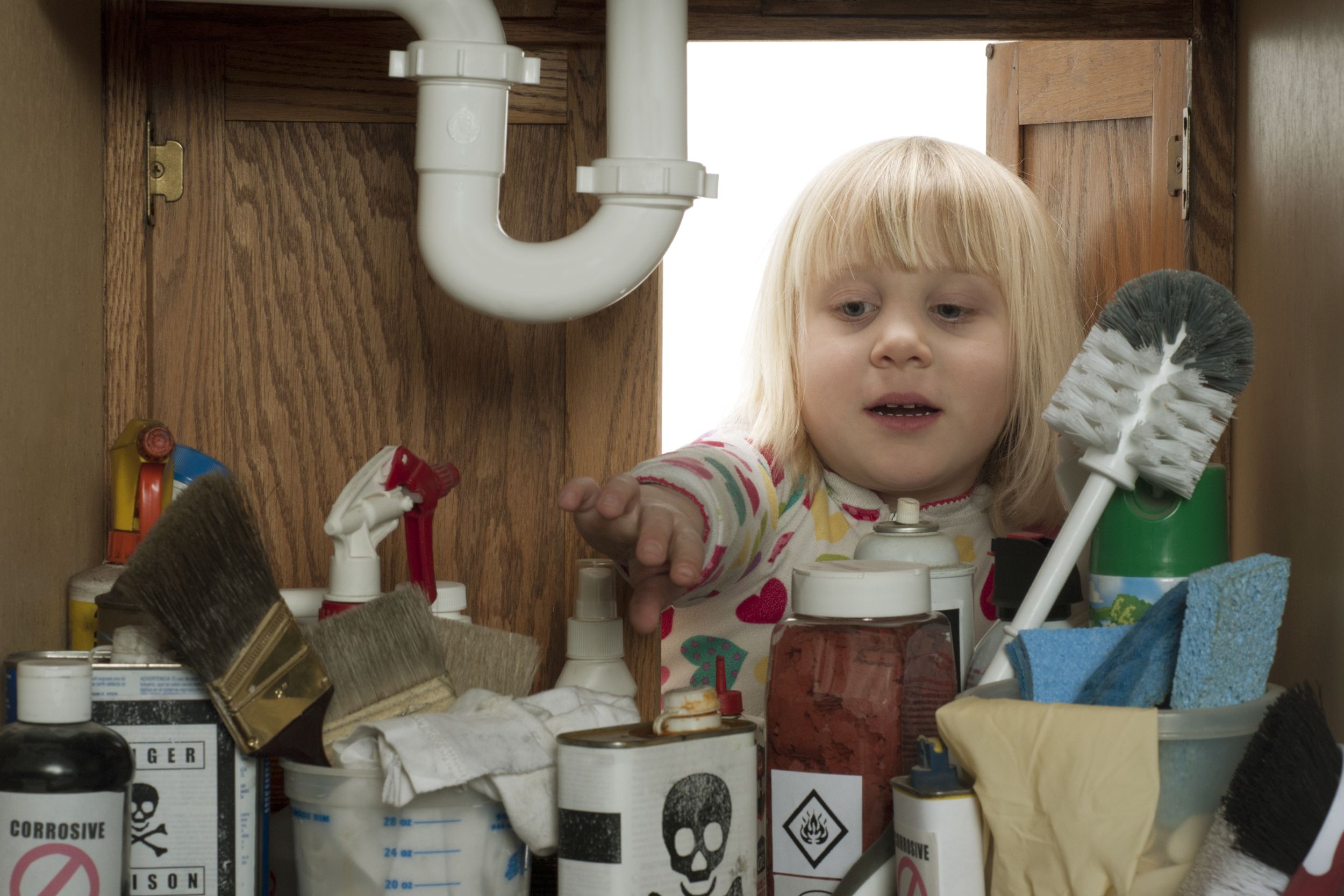little girl reaching under sink
