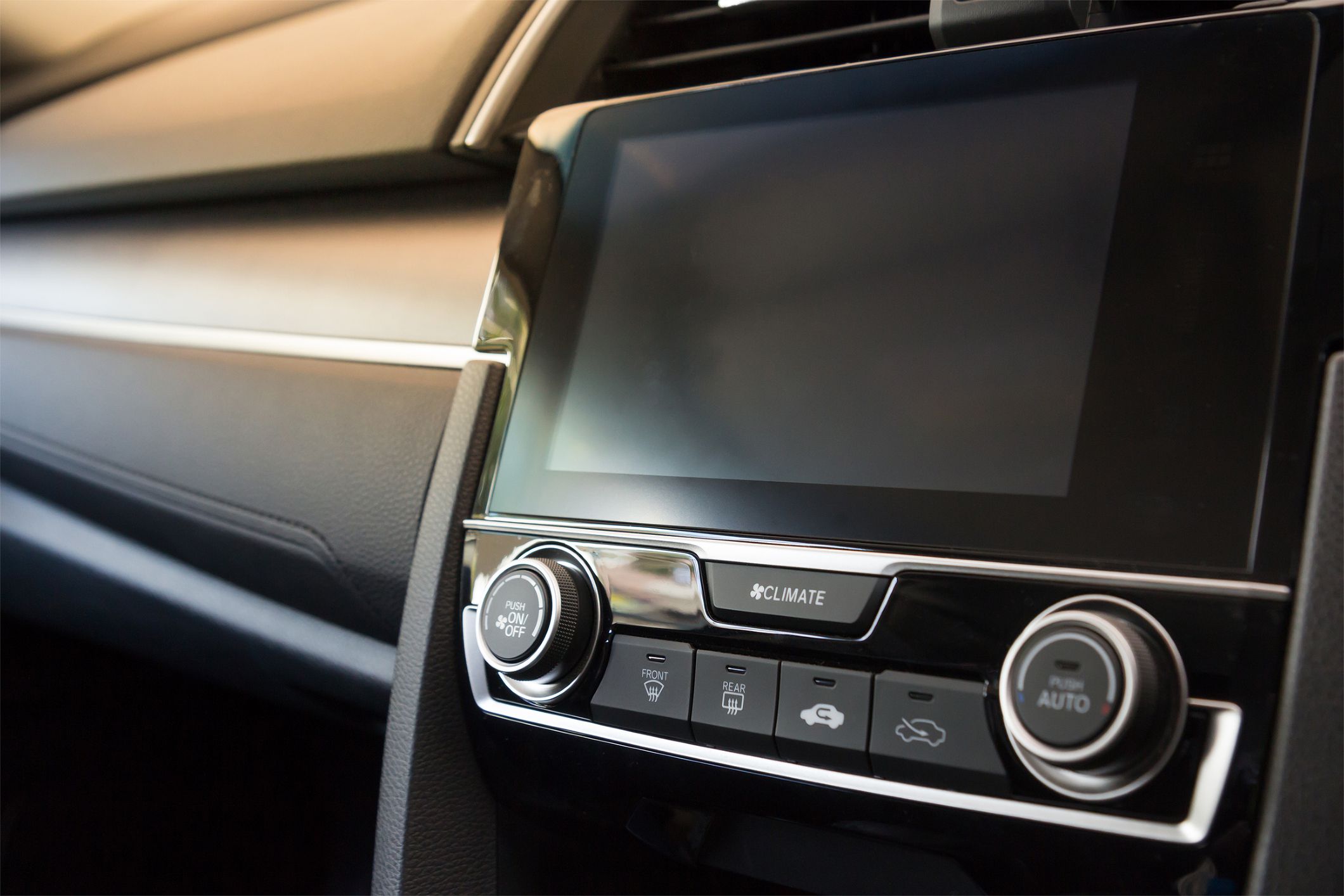 Car touchscreen with air conditional and radio buttons, closeup on the right side, left side showing dashboard leading up to touchscreen