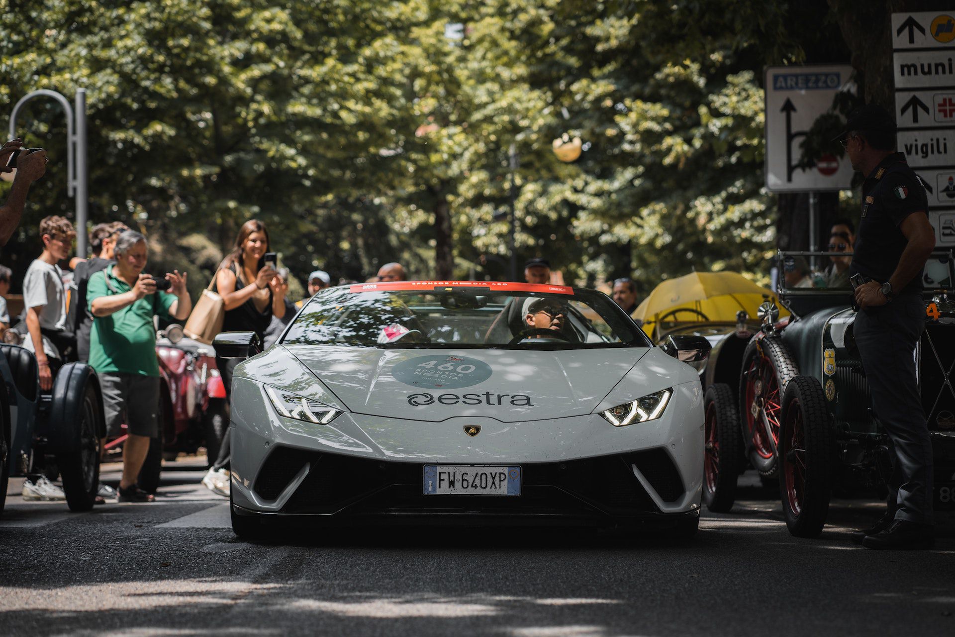 People taking photos of a white ferrari on a street