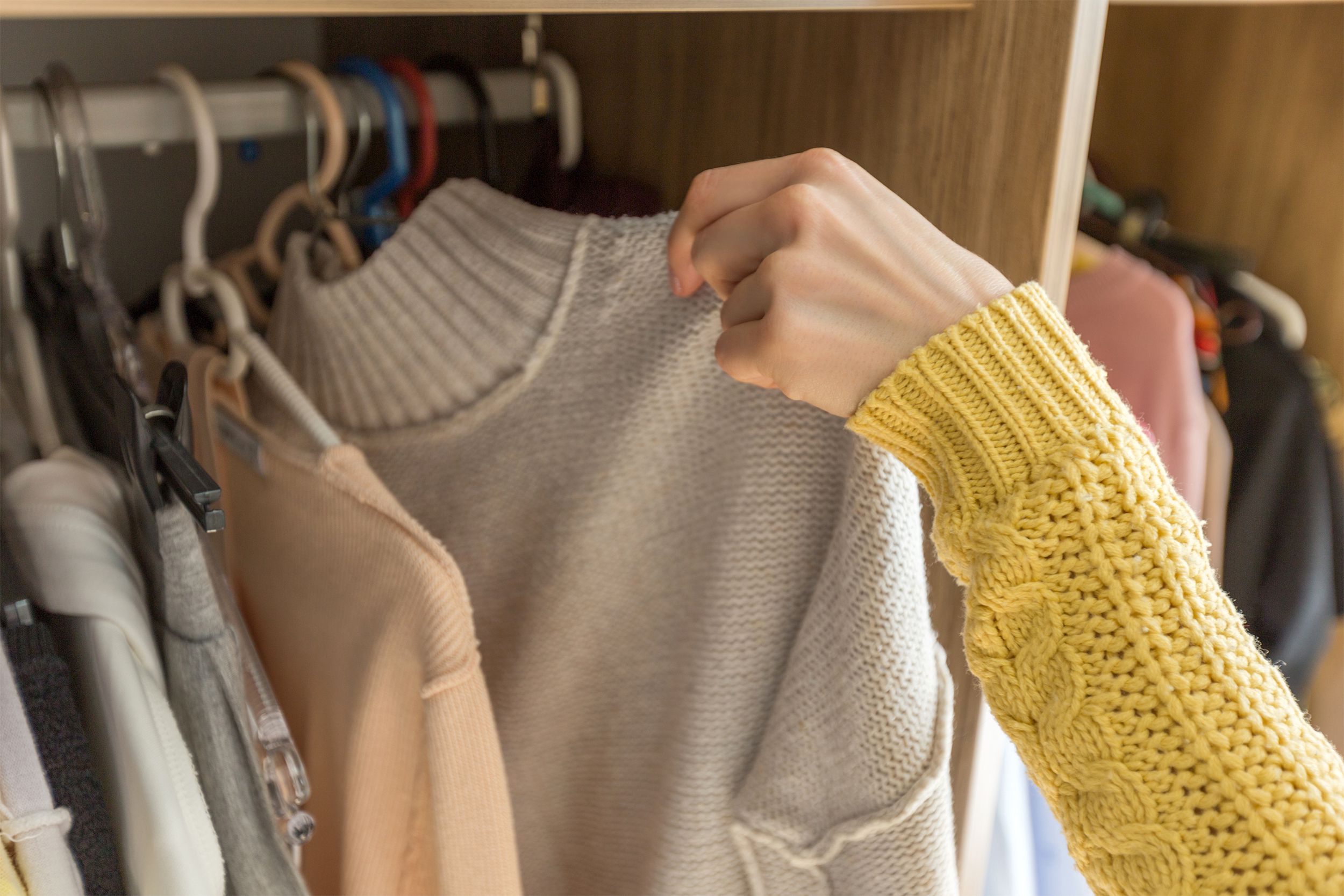 Holding a sweater in the closet