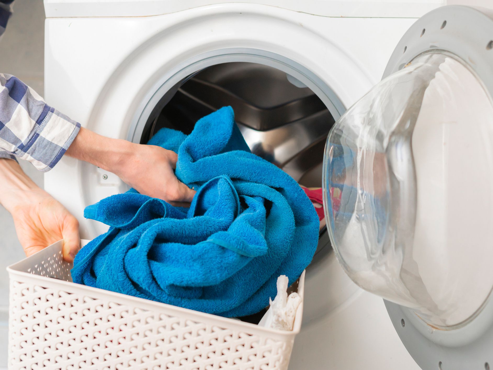 persons hand put dirty clothes in the washing machine