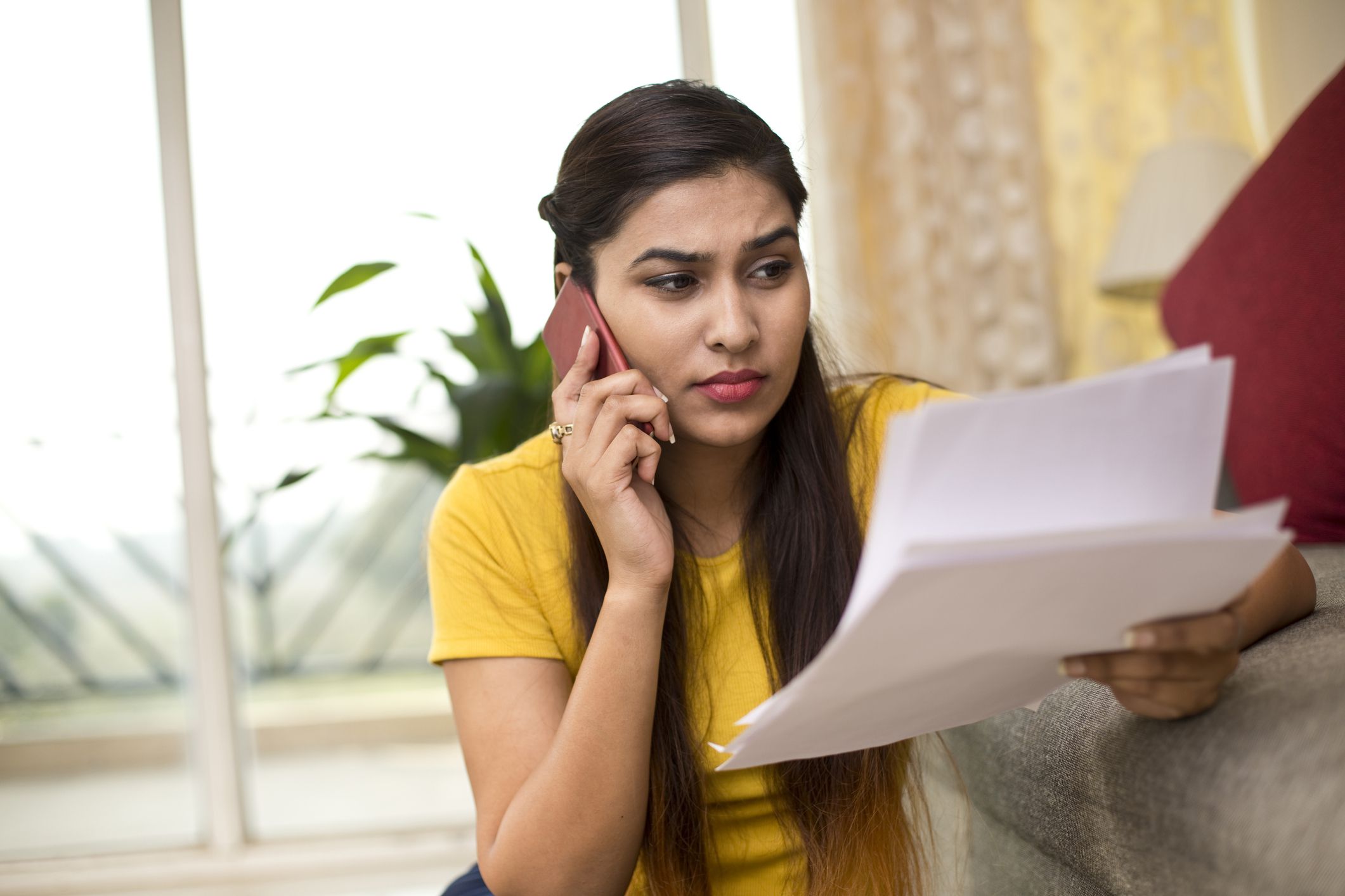 frustrated women looking at papers on phone