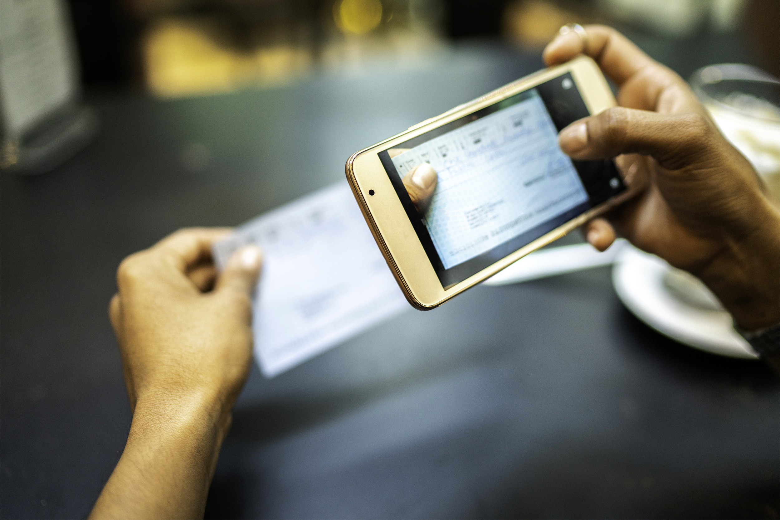 woman depositing check by phone in the cafe
