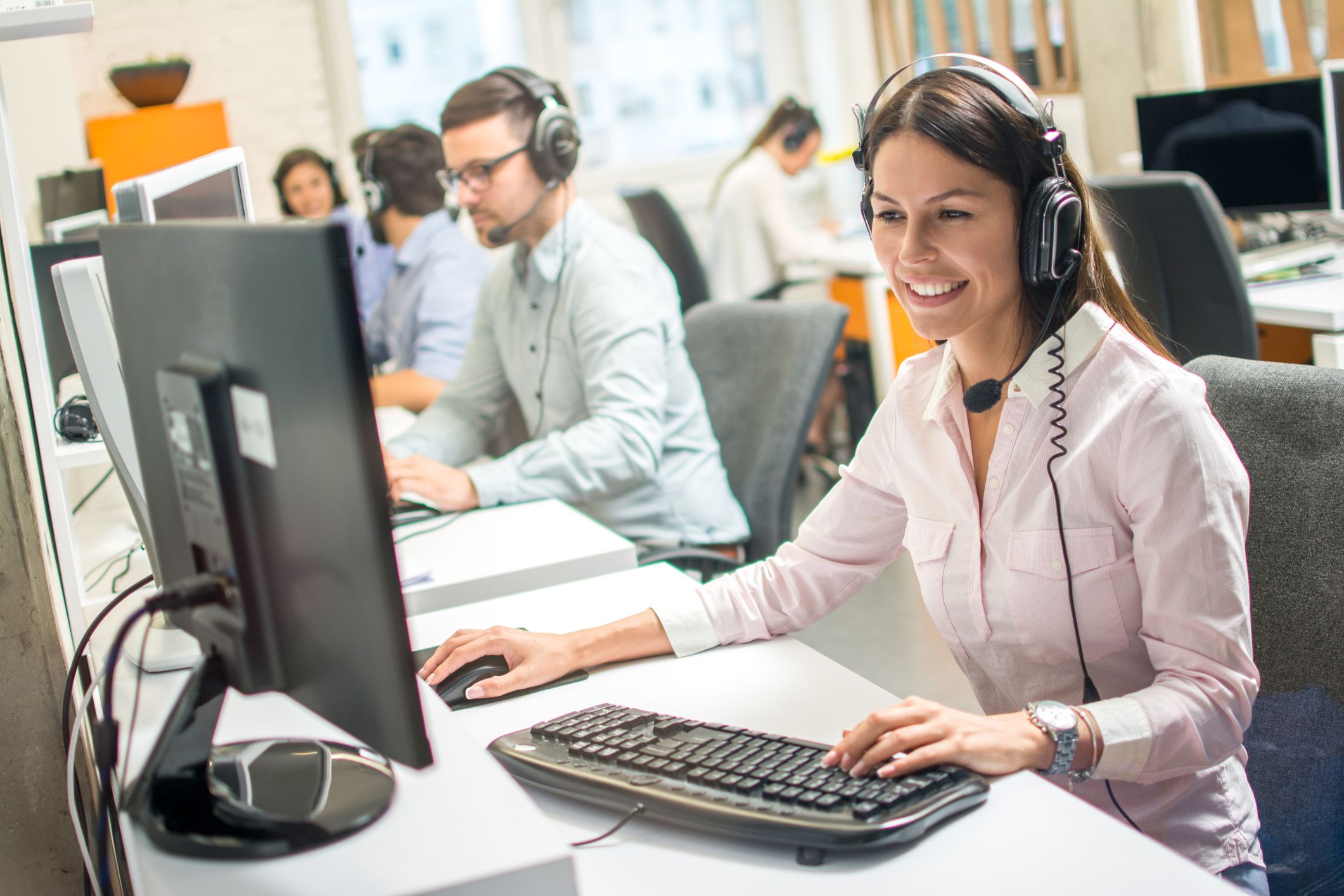 Friendly female operator consulting client on hotline in call center