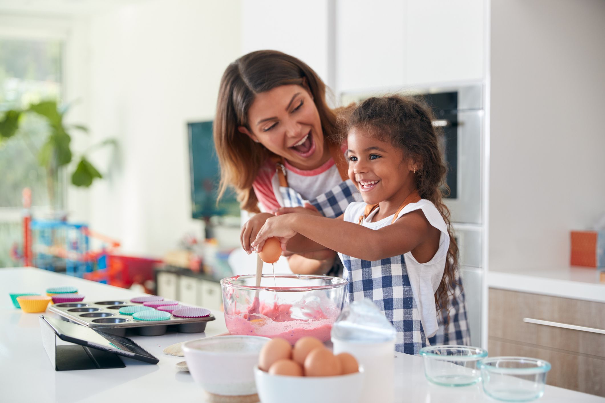 Hispanic Mother And Daughter Having Fun In Kitchen At Making Cake Together